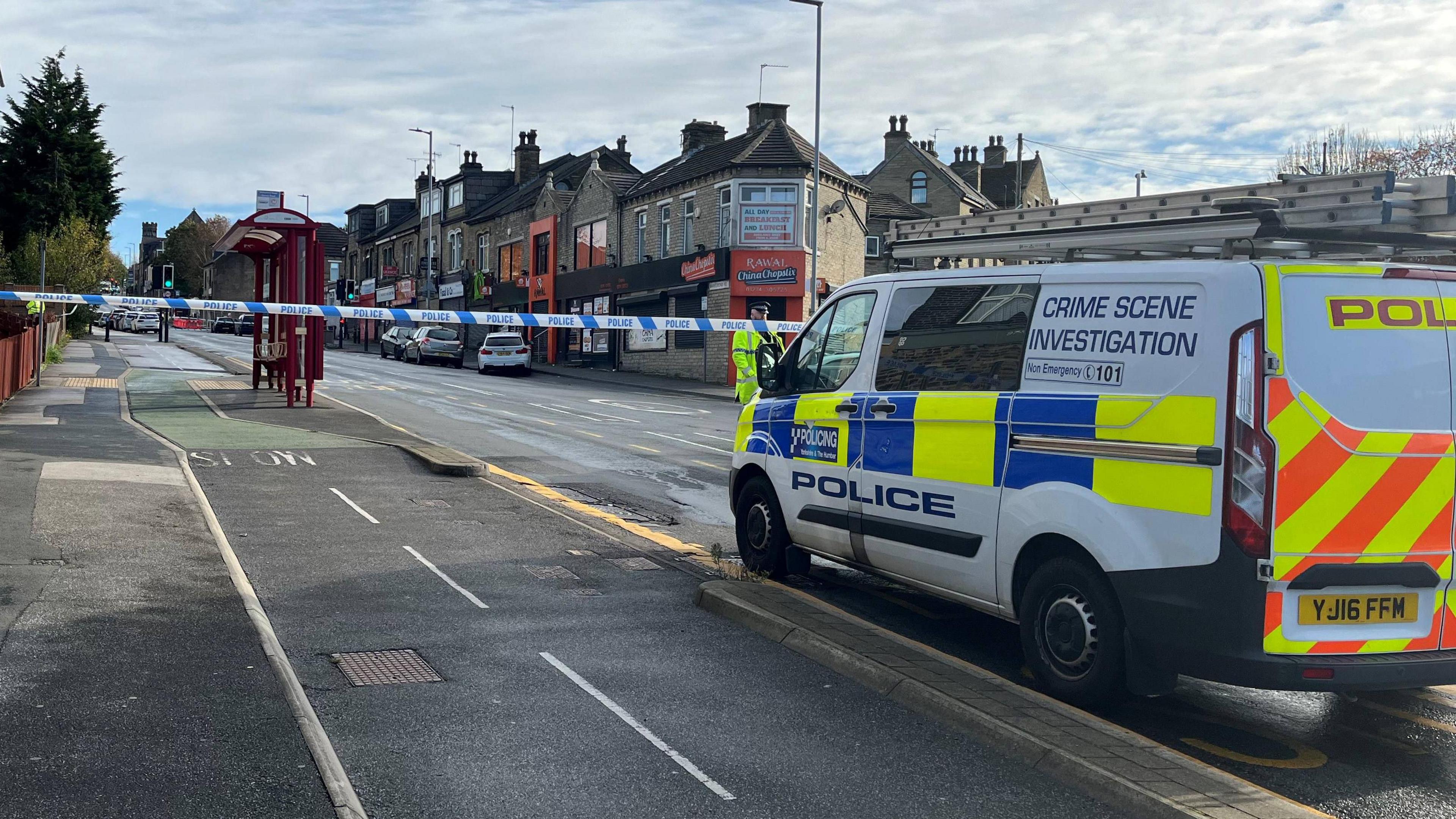 A police van is parked on a street cordoned off with police tape.