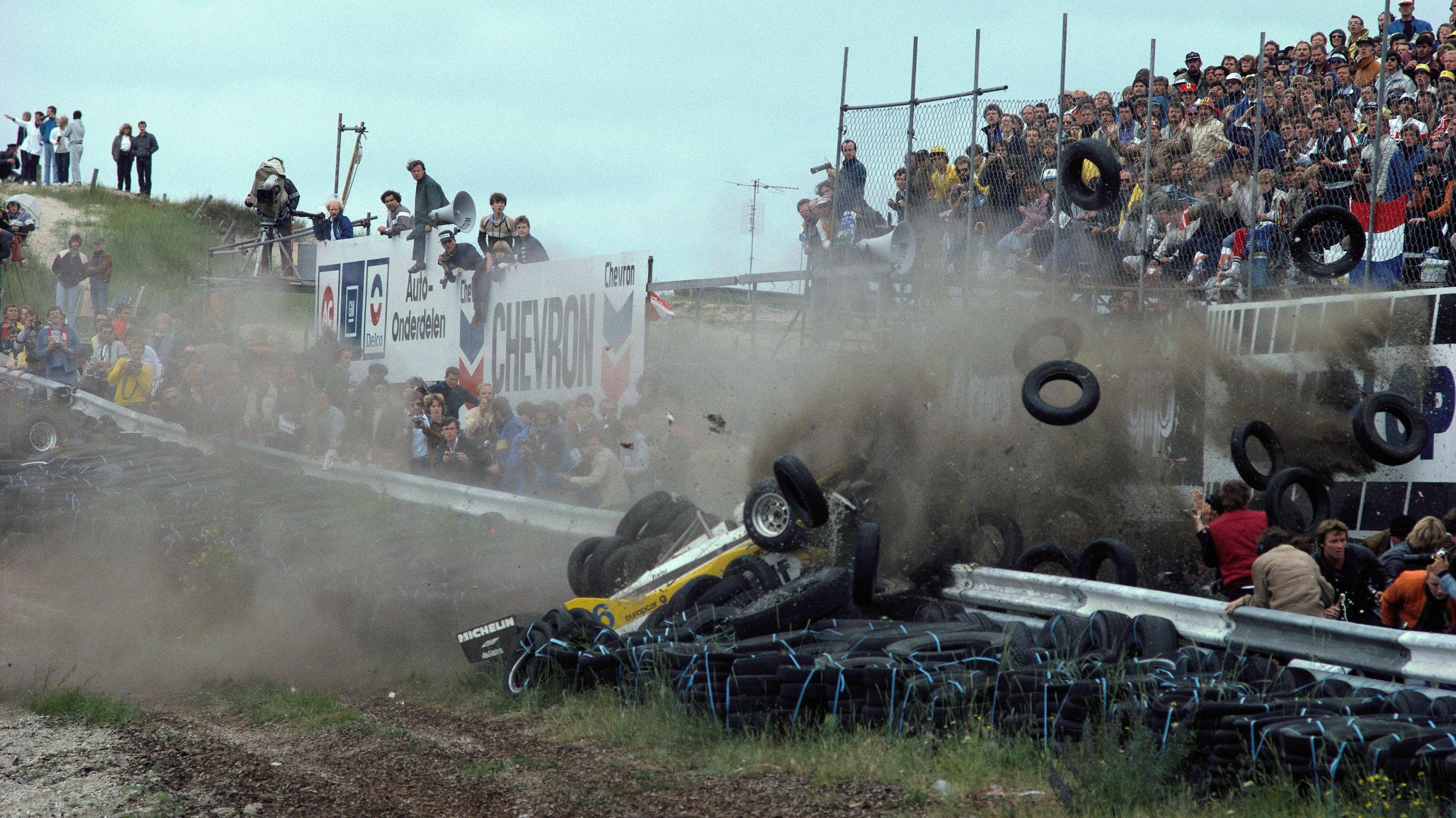 Spectators run from the scene of the accident, and tyres and dust fly into the air, as Rene Arnoux crashes his Renault during the 1982 Dutch Grand Prix