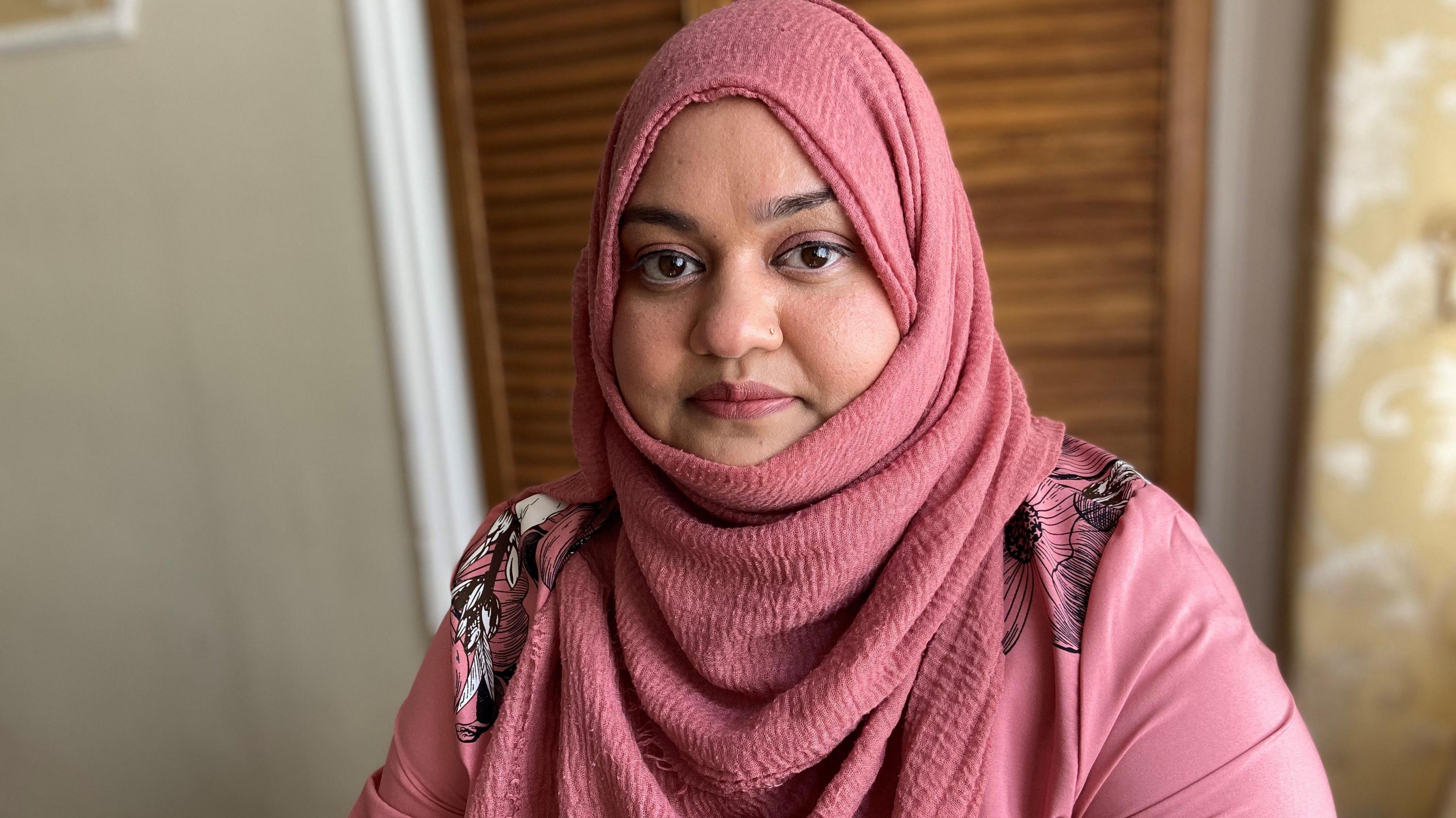Sahdia looking into the camera. She is wearing a pink hijab and pink top.