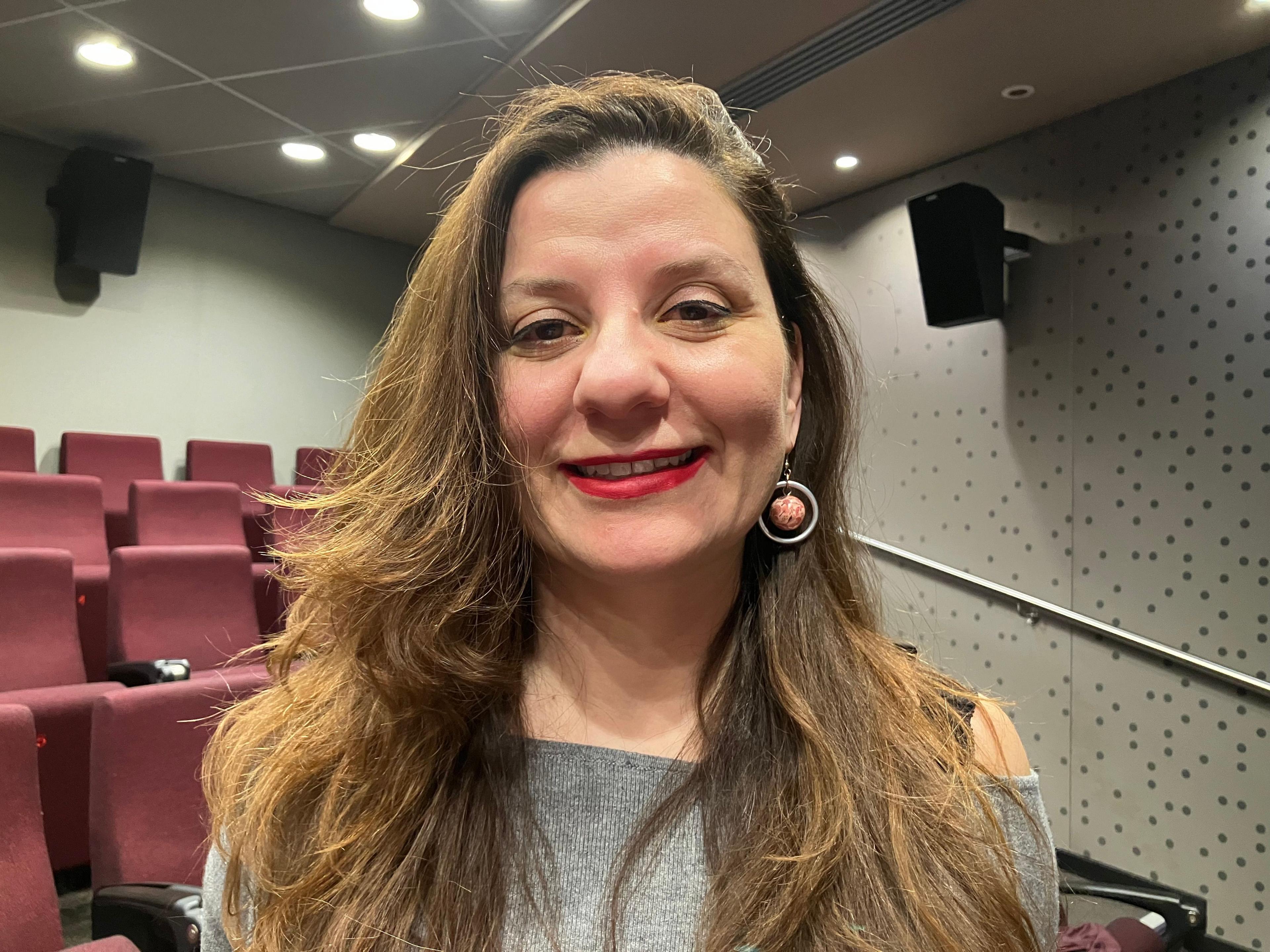 Lara Kozah smiles at the camera with red seats behind her