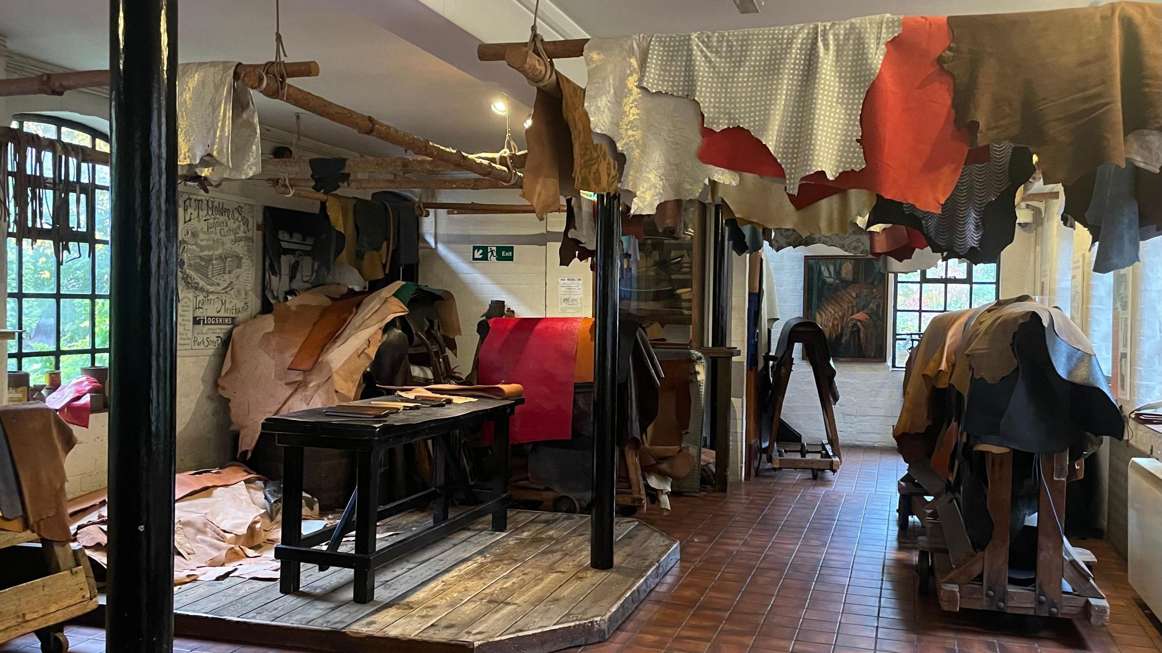 a leather museum displaying lots of different cuts of leather in an mock up of an old workshop