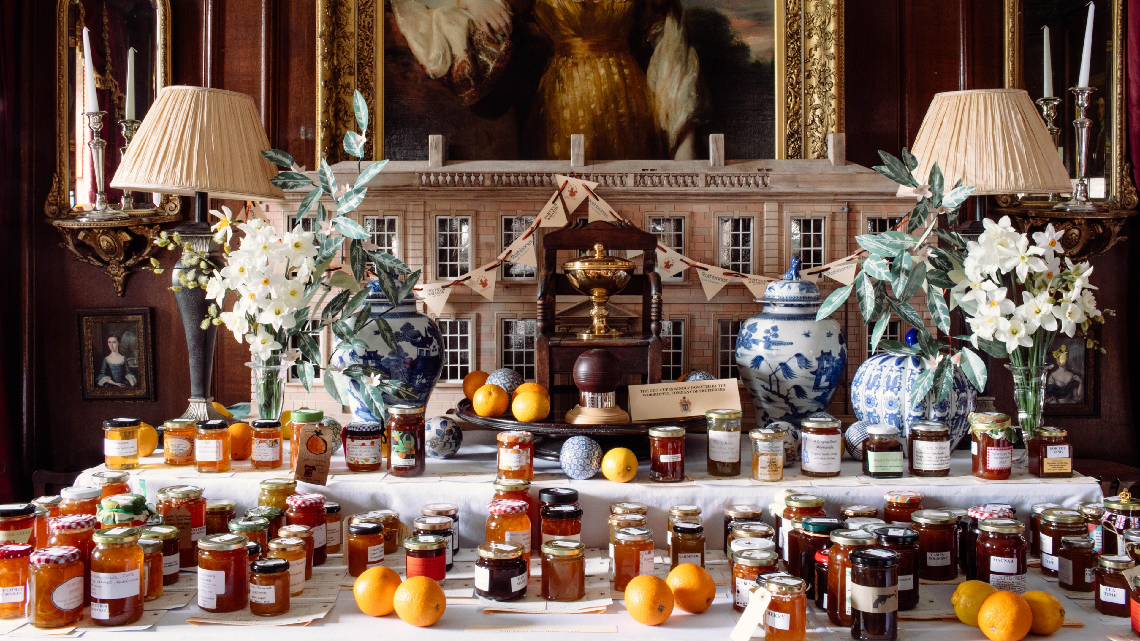 Jars of marmalade displayed on a table with a model of Dalemain House and half an oil paintingbehind