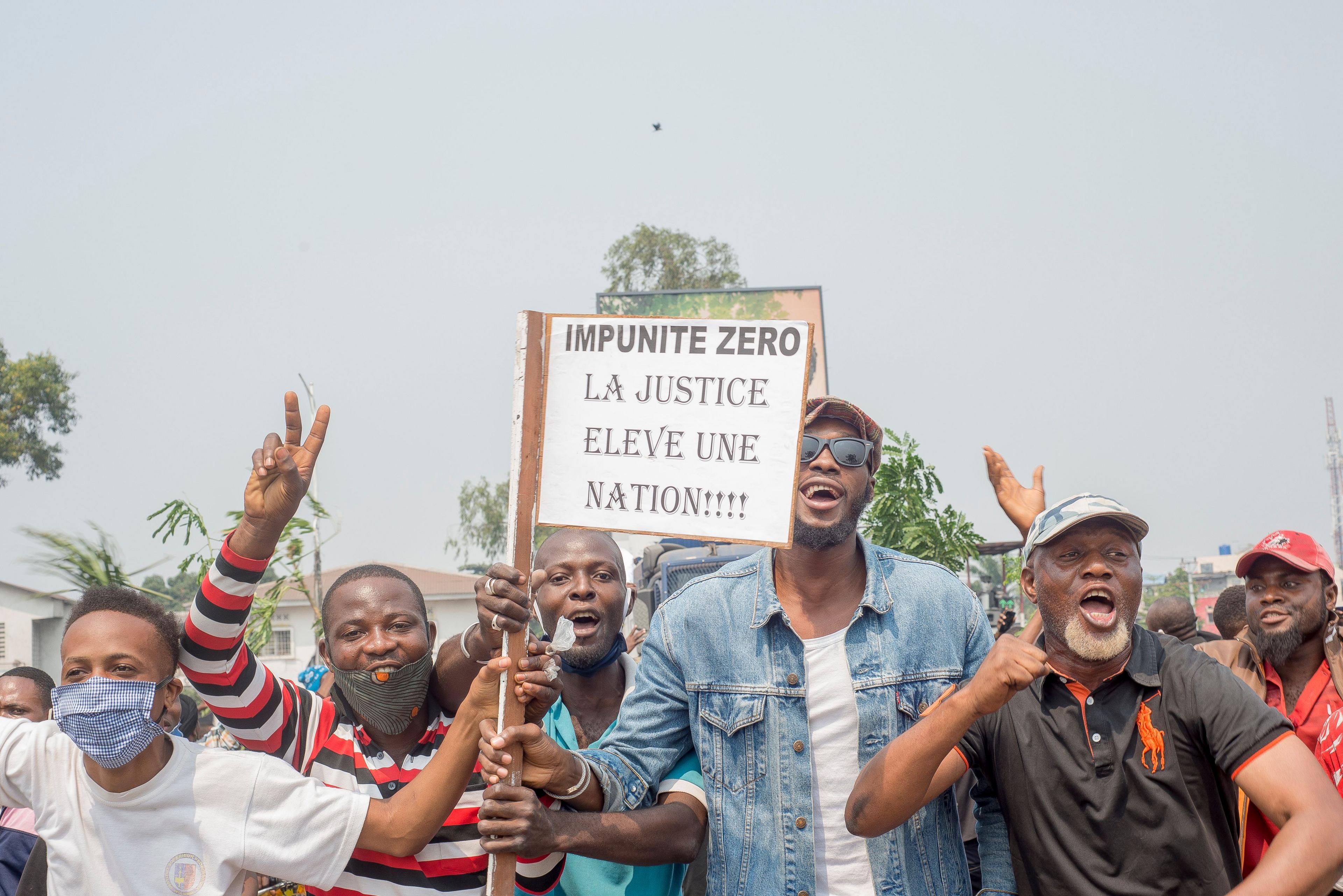 Protesters, including many motorbike-taxi drivers, hold placards while protesting and facing the police around parliament on for the second consecutive day in Kinshasa, DR Congo - 24 June 2020