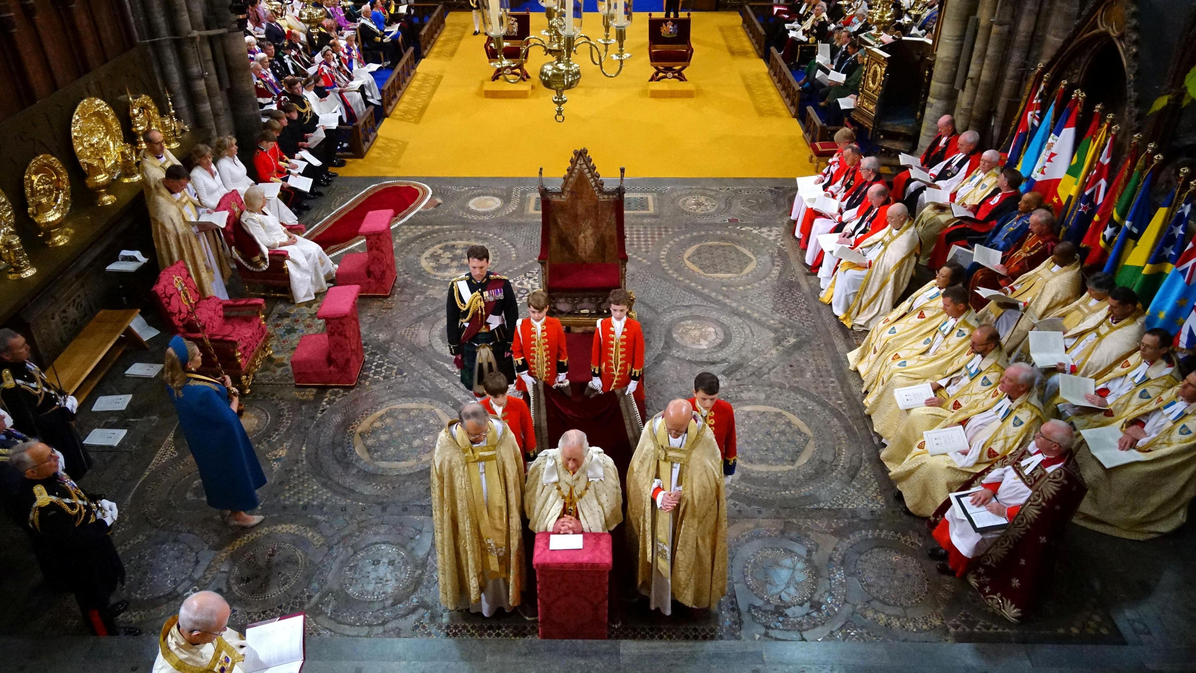 King Charles kneeling in front of the Coronation Chair