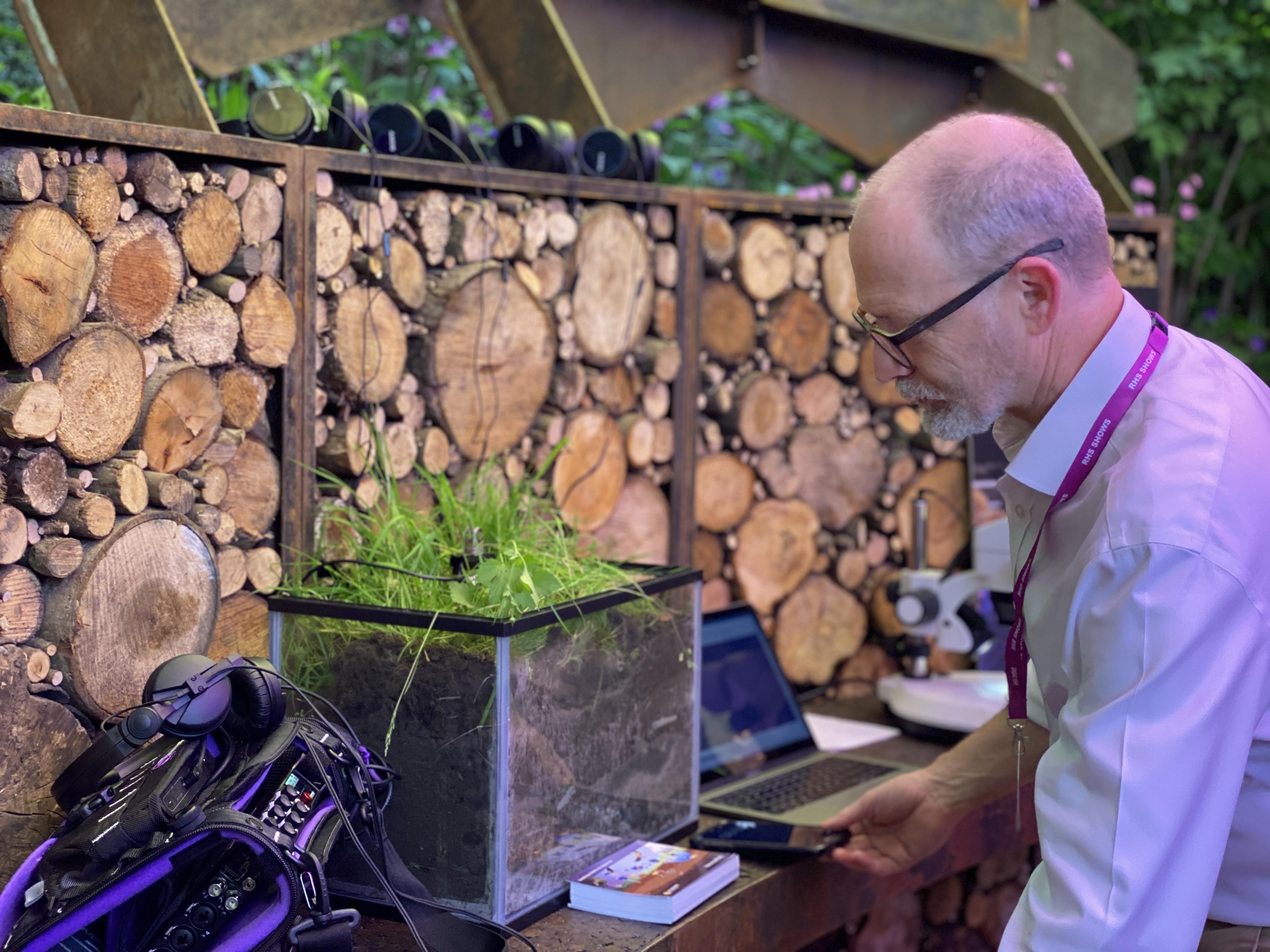 Man looking at fish tank full of soil and grass