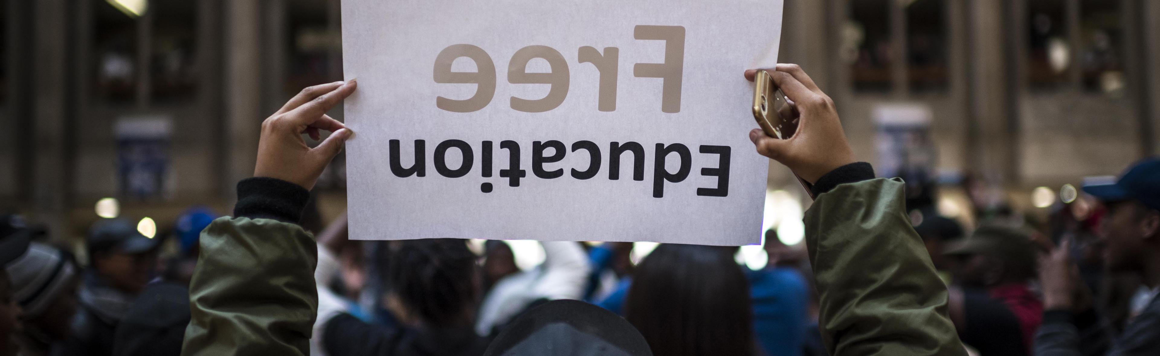 A student holds a free education poster during protest over tuition fees