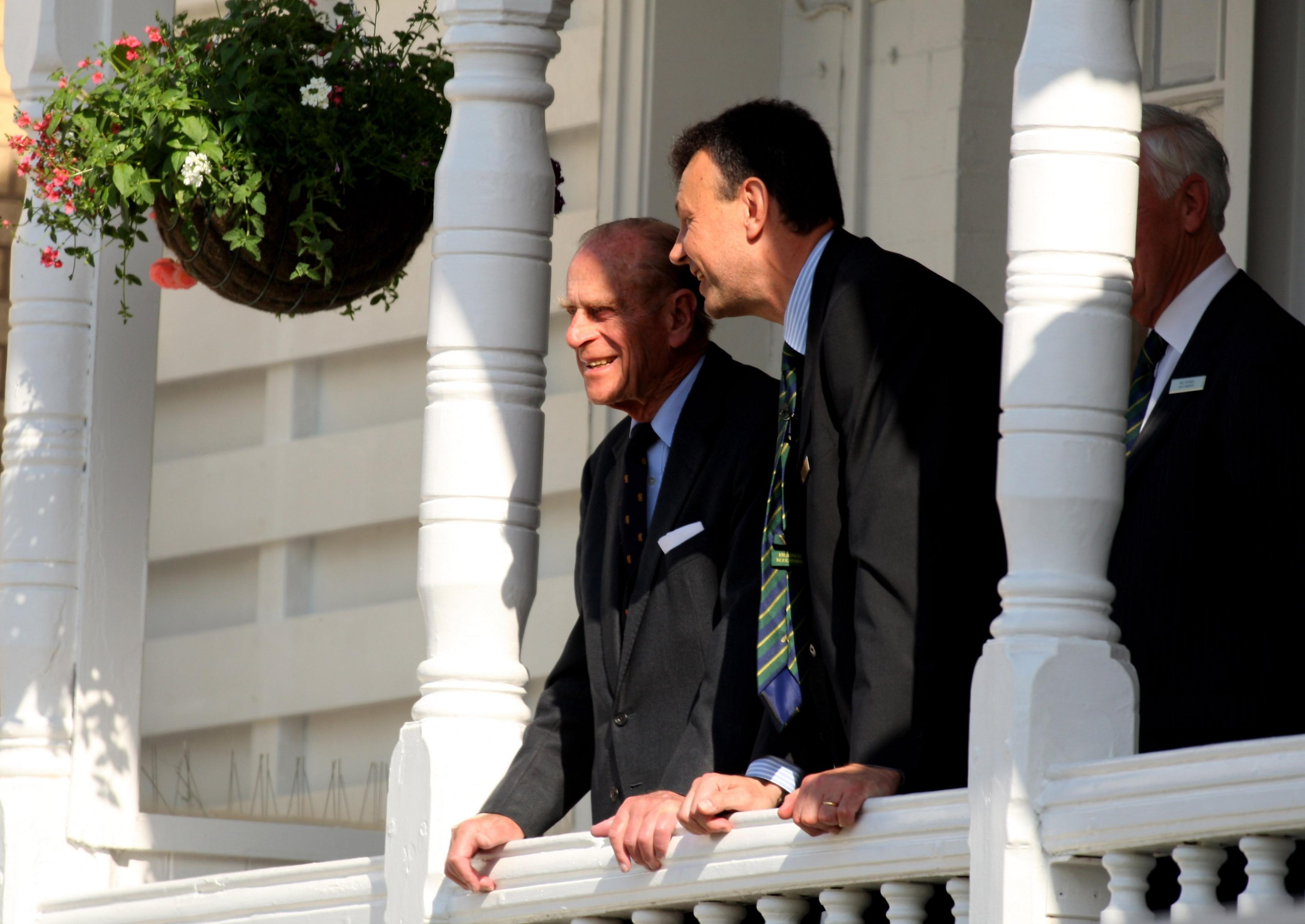 Prince Philip, Duke of Edinburgh watches play from a balcony with former chief executive Derek Brewer