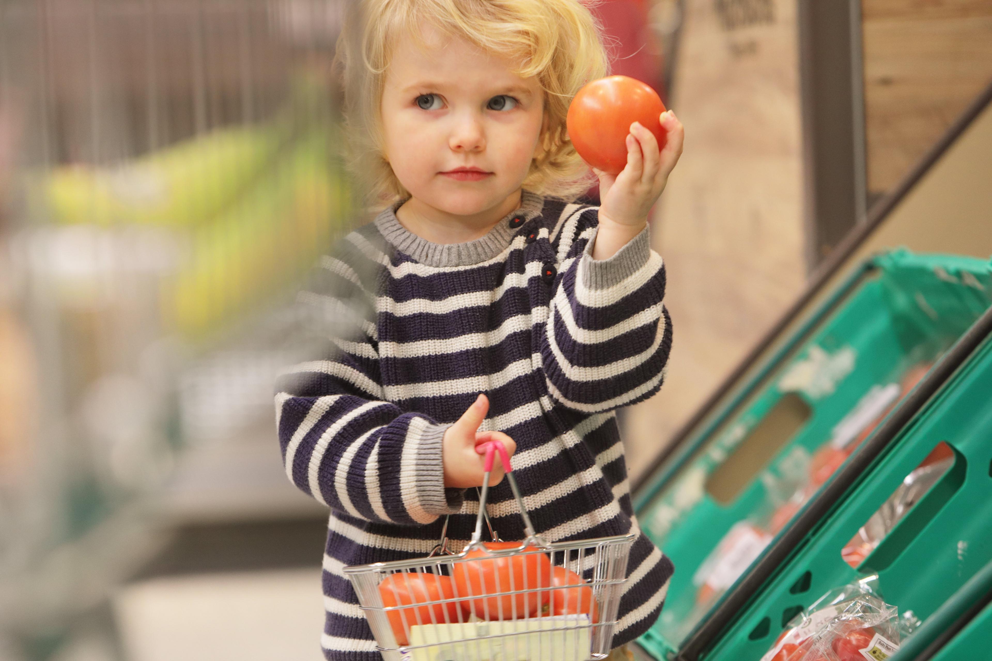 Young child holds apple in supermarket