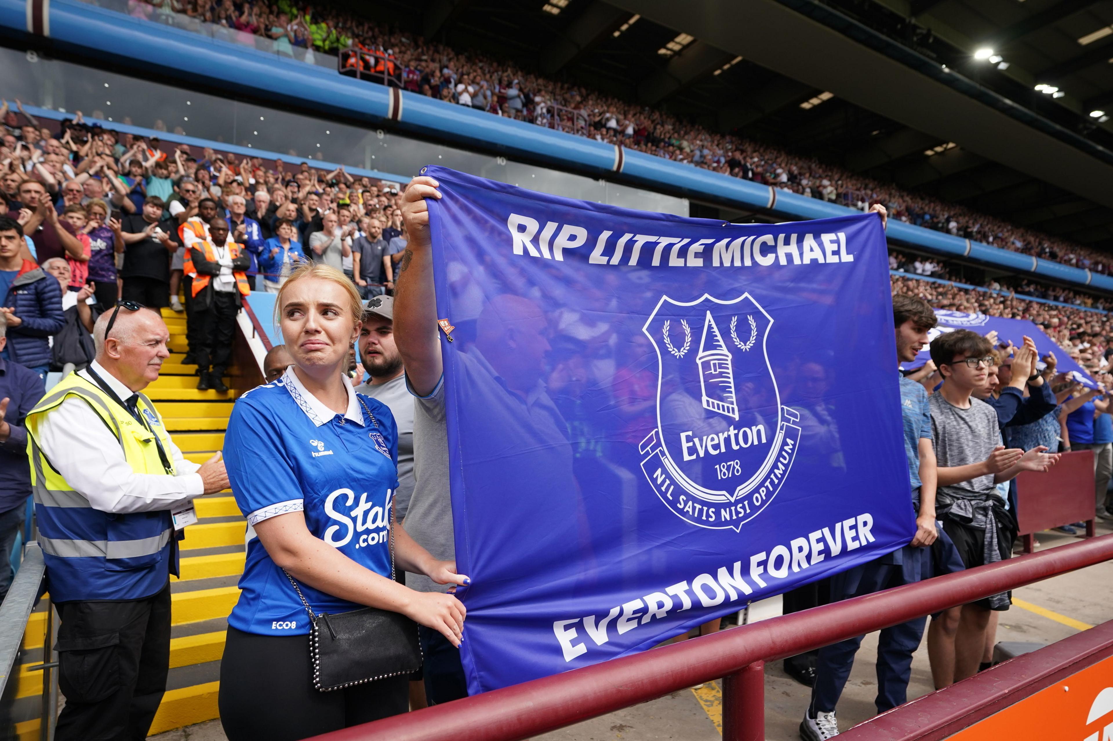 Fans hold up a flag in honour of construction worker Michael Jones baring the message: 'RIP Little Michael, Everton Forever.'