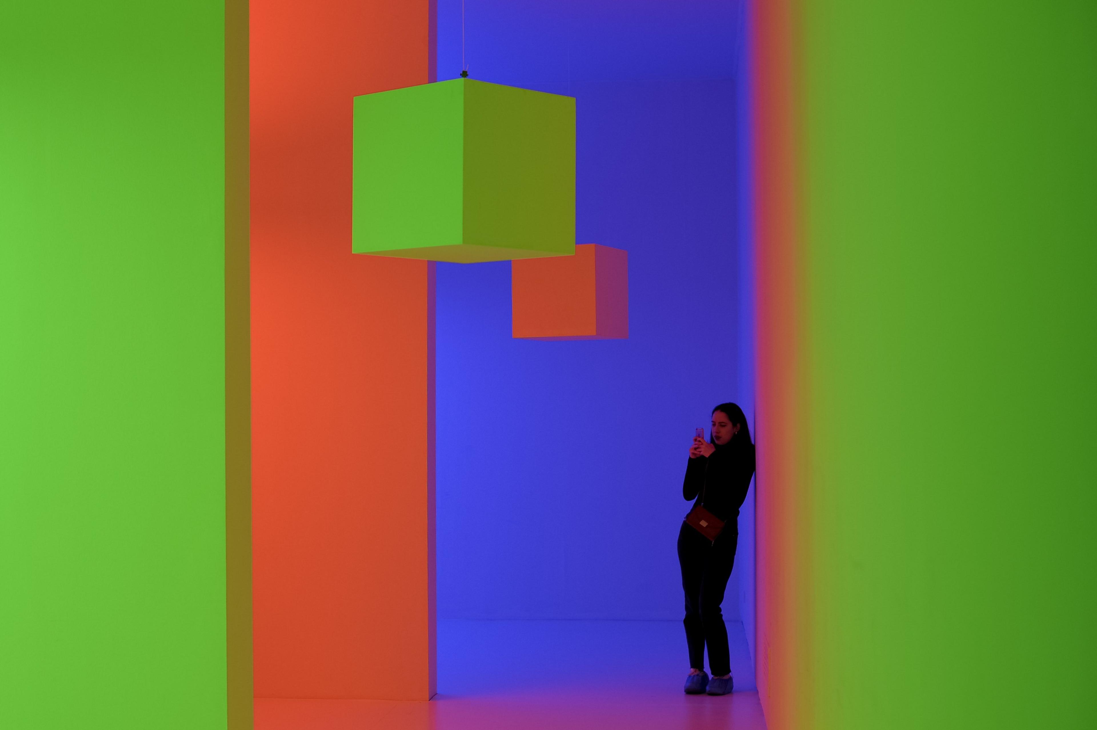 A visitor takes a picture of an artwork by Venezuelan artist Carlos Cruz-Diez entitled 'Chromosaturation' at the art exhibition 'L'emozione dei COLORI nell'arte'