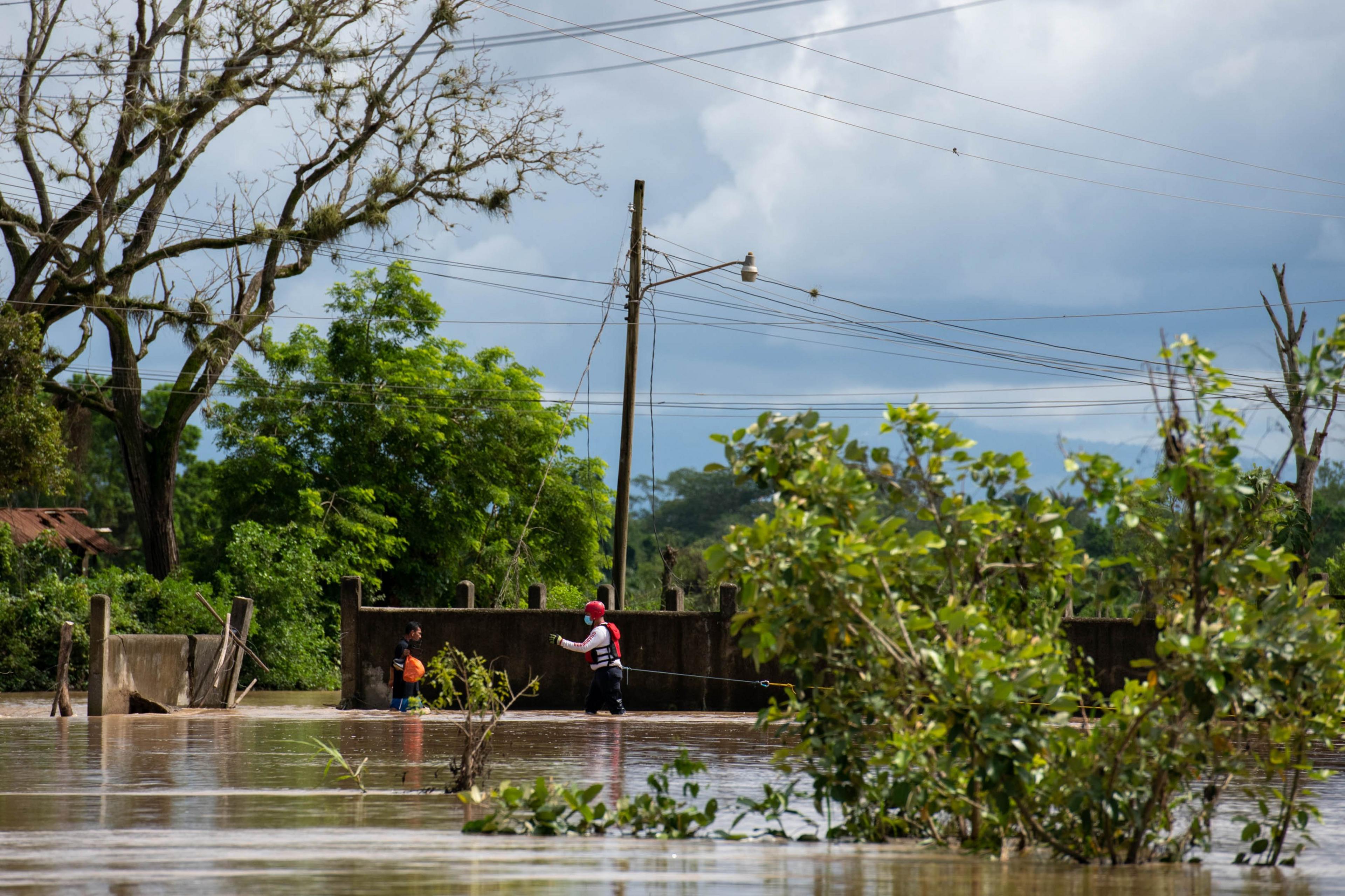 .Juan Argueta stands in flood waters as a rescue worker from the Red Cross approaches him