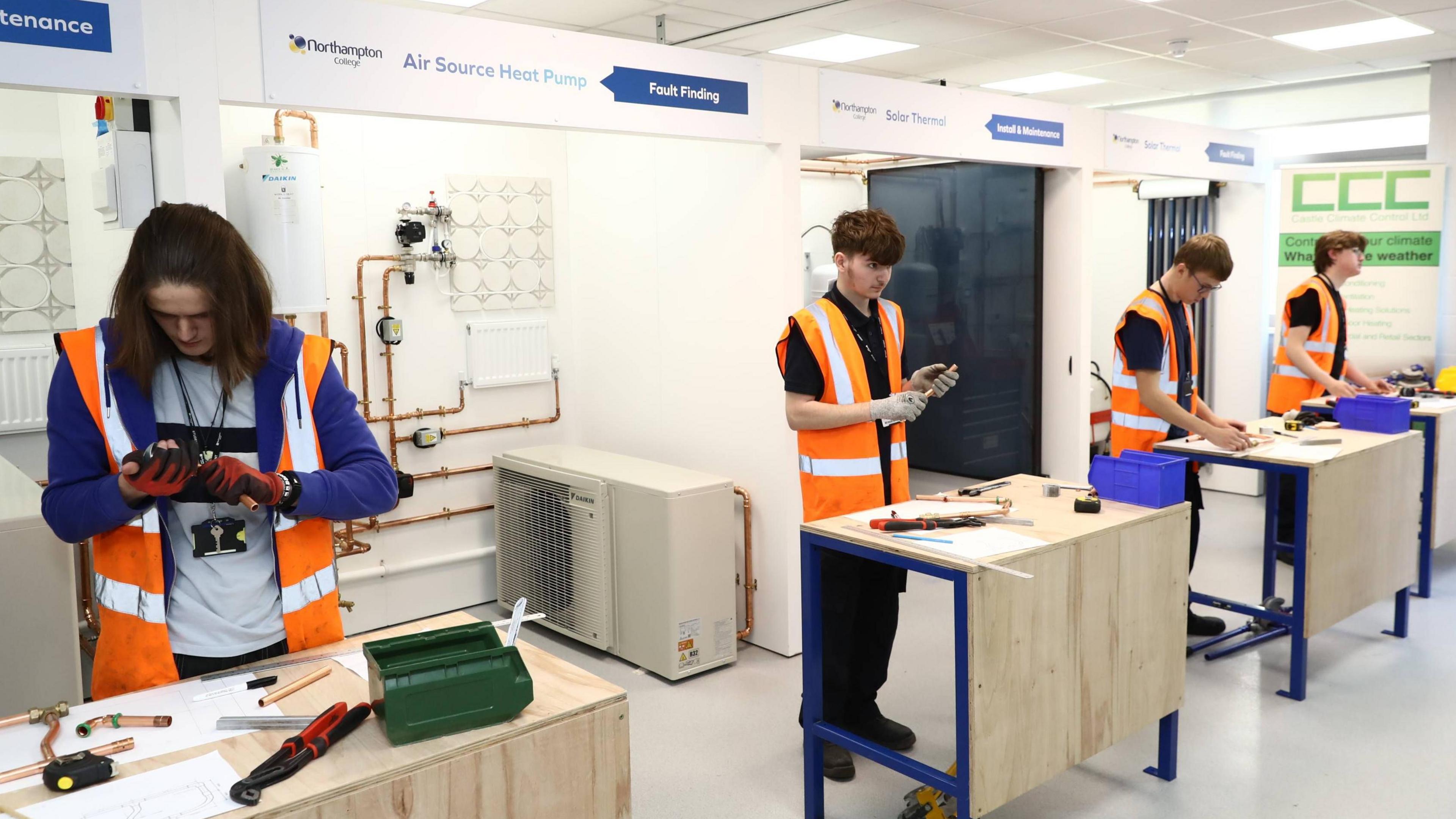 Students wearing fluorescent jackets working with metal materials in a learning environment