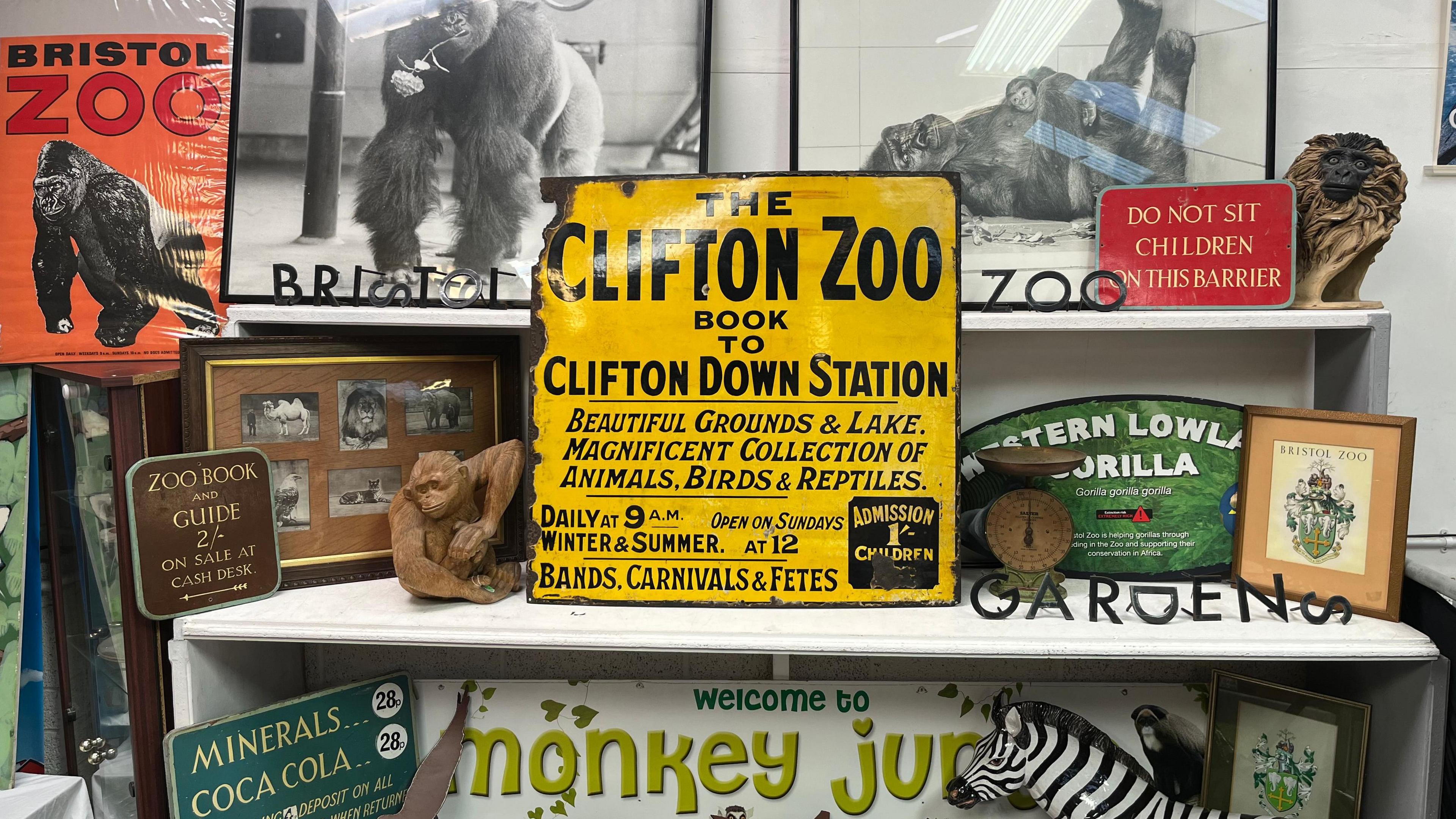 A collection of items from Bristol Zoo Gardens that are up for auction including yellow signage, posters, black and white photos of gorillas and monkey sculptures