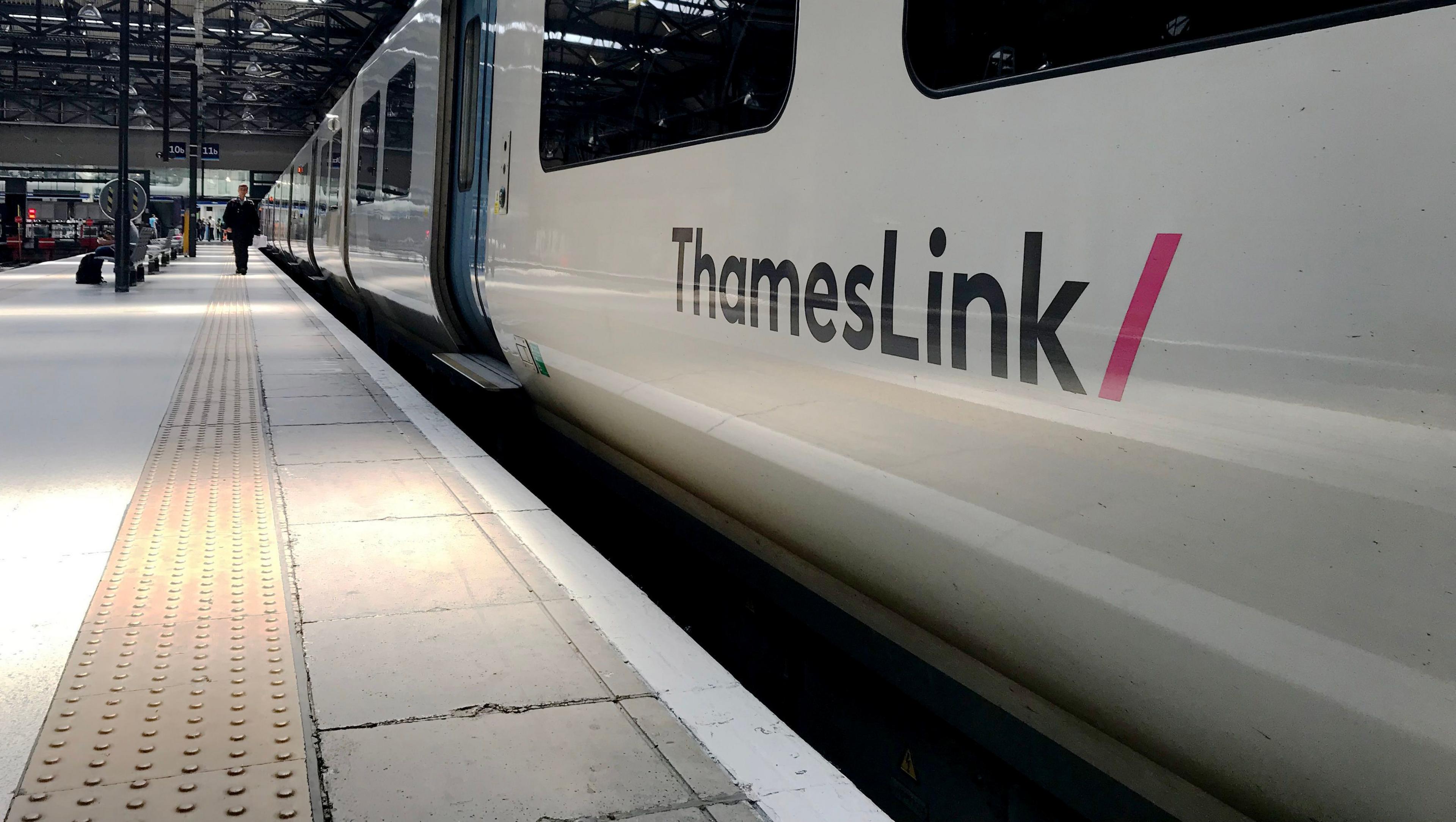 A general view of a Thameslink train at King's Cross Station in London. It shows the train parked at the station platform. A person can be seen in the distance walking along the platform.