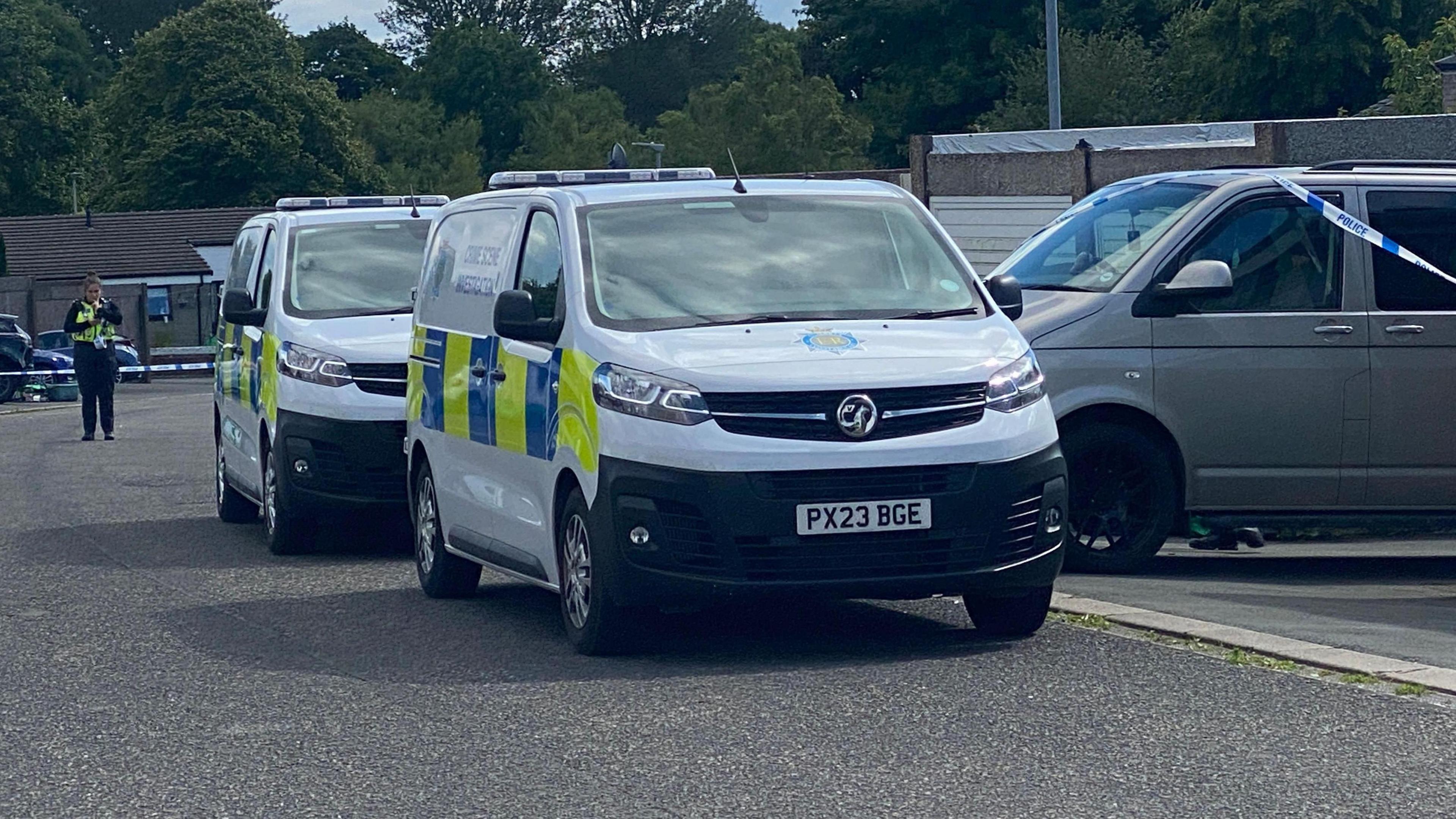 Police cars at the scene at Whernside in Carlisle, with an officer in the distance