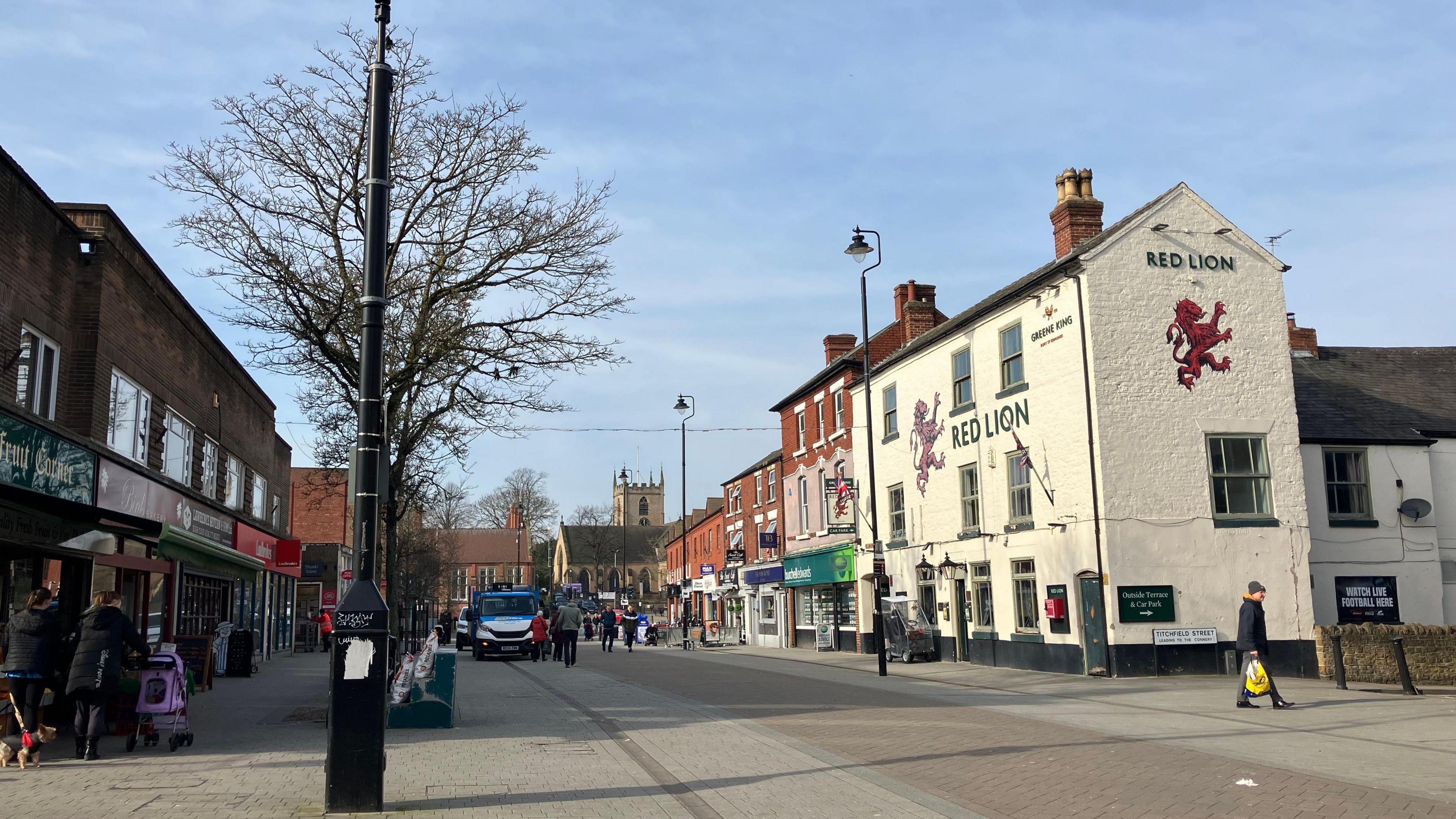 Hucknall High Street showing a traditional pub and series of Victorian buildings on one side, then more modern flat roofed units on the other side