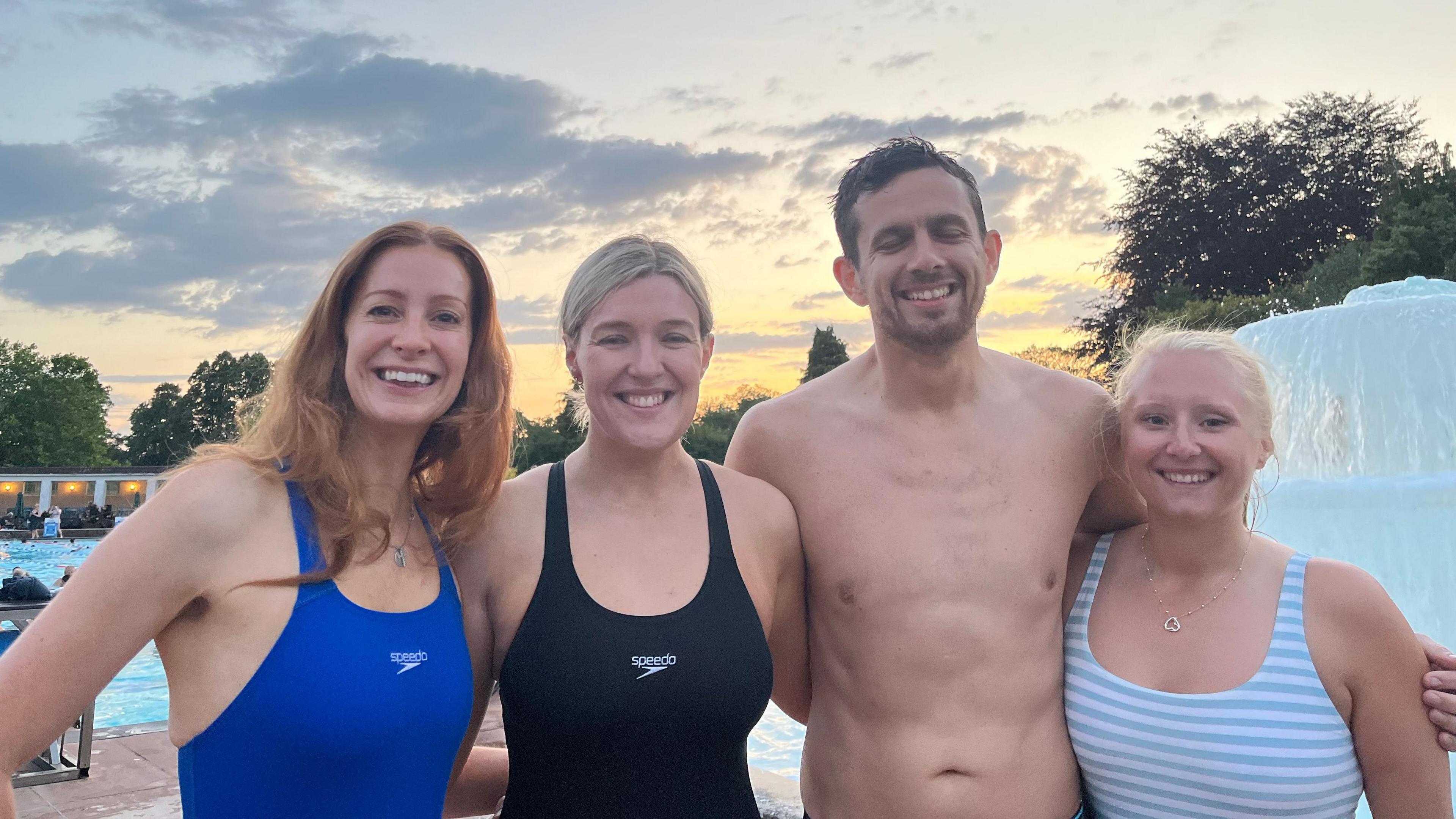 A group of four people in swimwear smiling at the camera