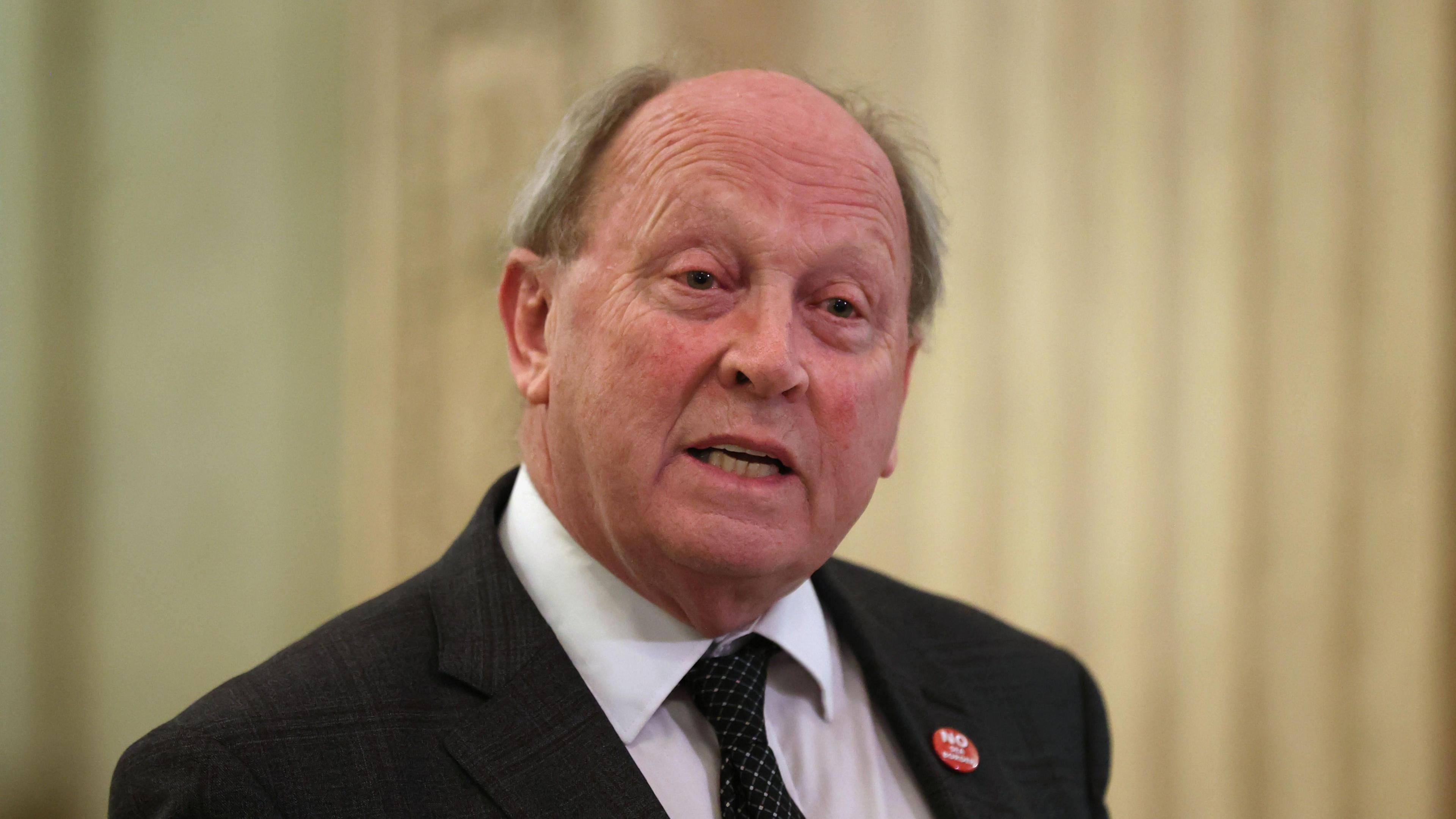 Jim Allister. He is bald, wearing a lack blazer, white shirt, black polka-dot tie and a red pin.