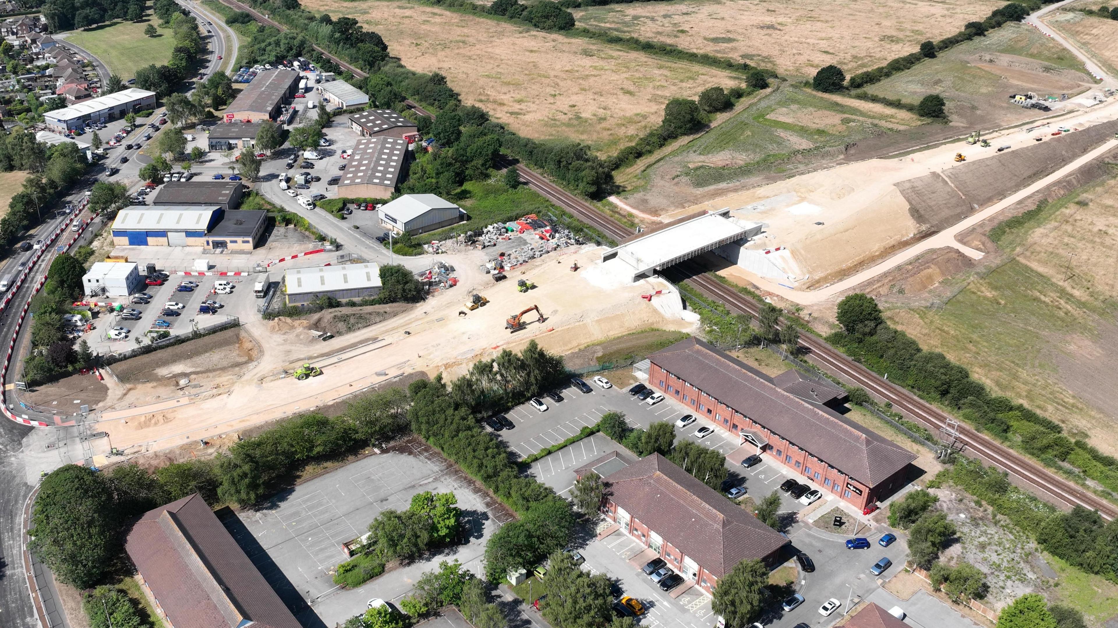 An aerial image showing a bridge being built over a railway line. Diggers and other heavy machinery can be seen.