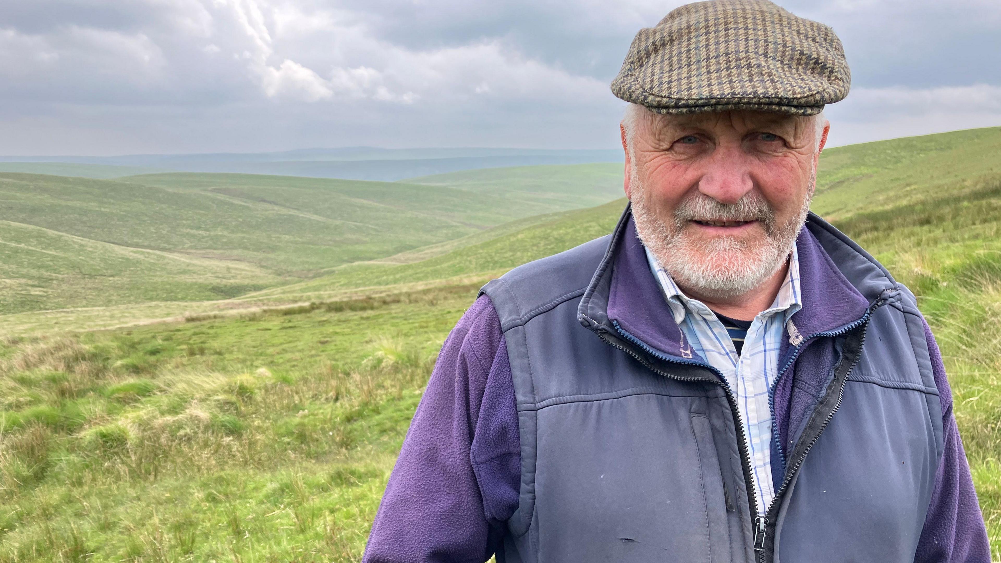 Llun o'r ffermwr Glyndwr Jones yn sefyll ar Lwybr y Mynaich