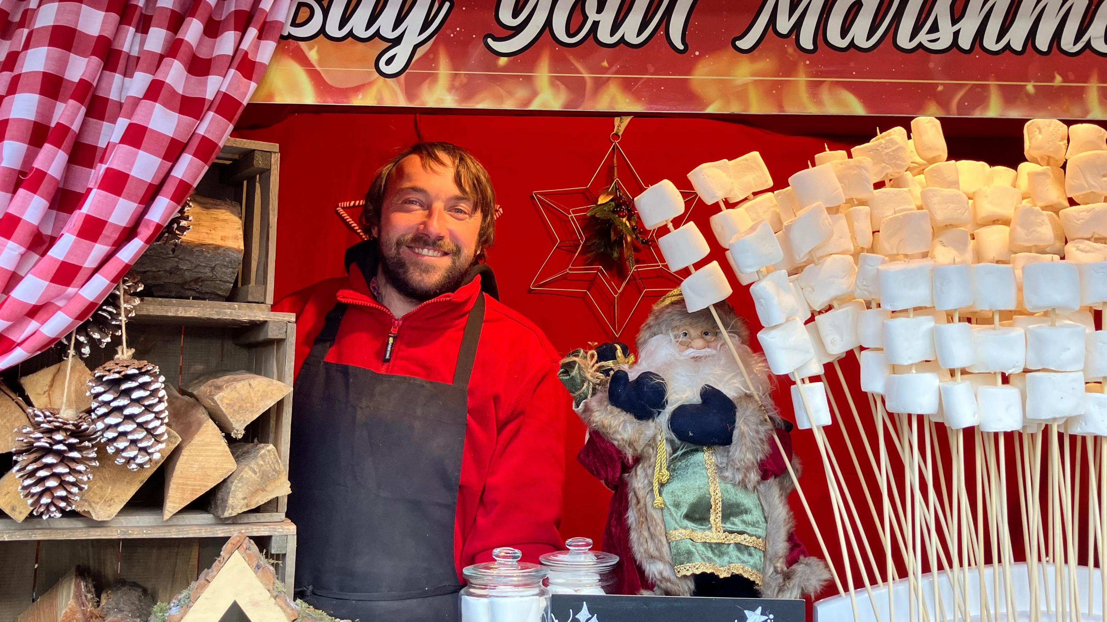 Dan Payne, who has mid-length brown hair, standing next to the marshmallows on sale at his stall.