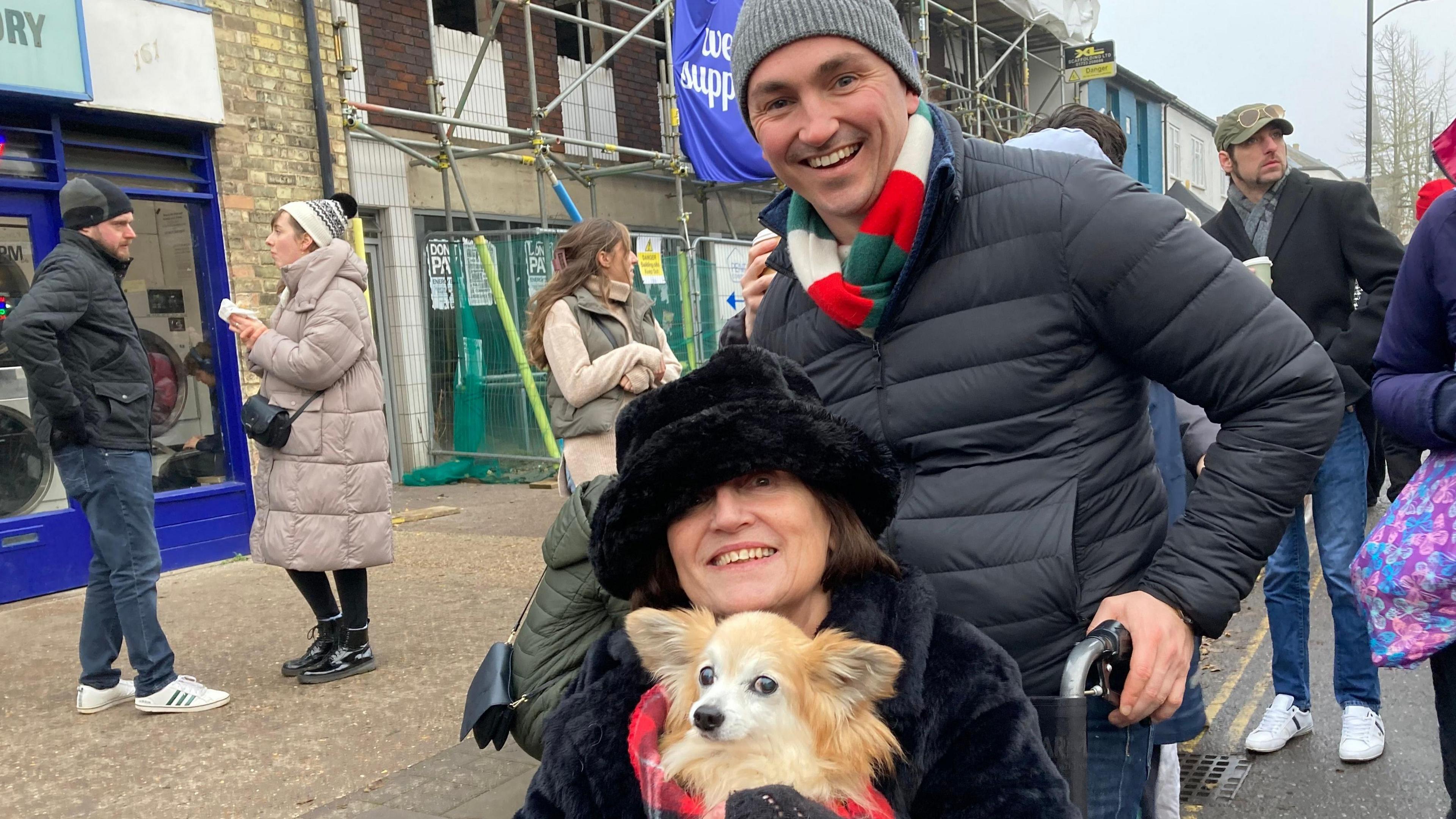 A man, woman and dog at a Christmas fair