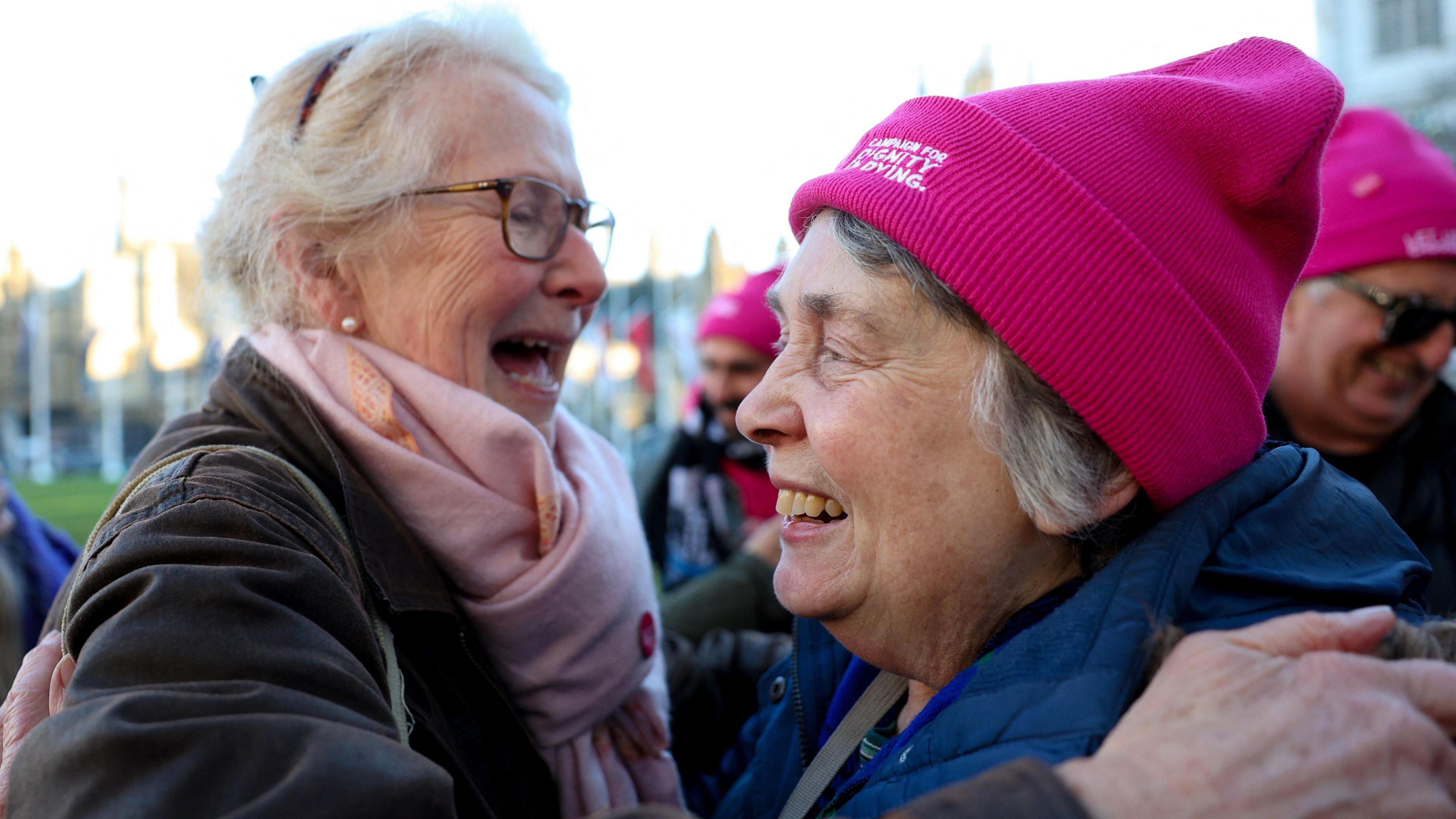 Two women taking part in a demonstration in support of assisted dying outside Parliament hug after the result of the vote is announced. One is wearing a pink hat reading: Campaign For Dignity In Dying