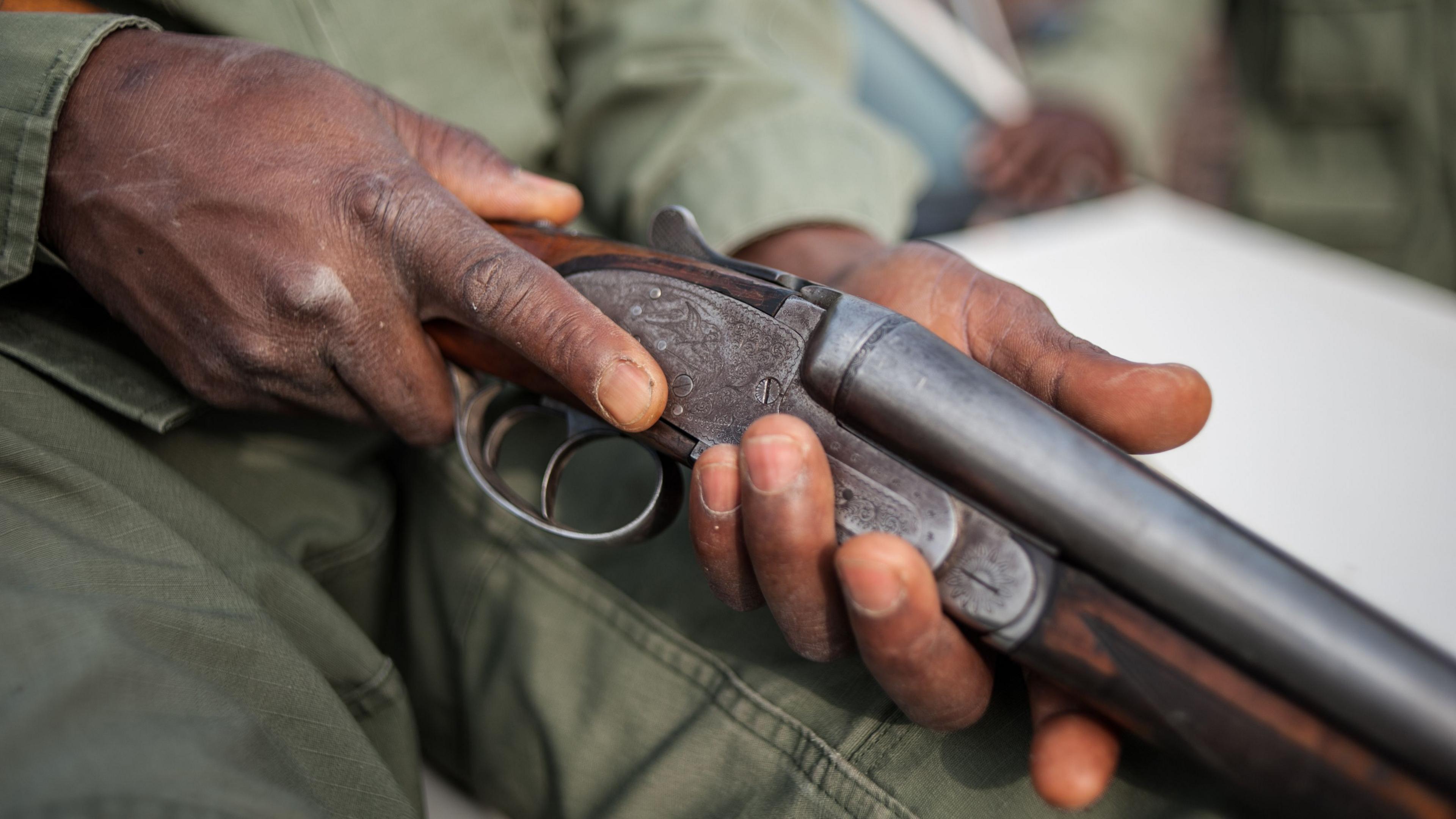 Image shows two hands holding a shotgun