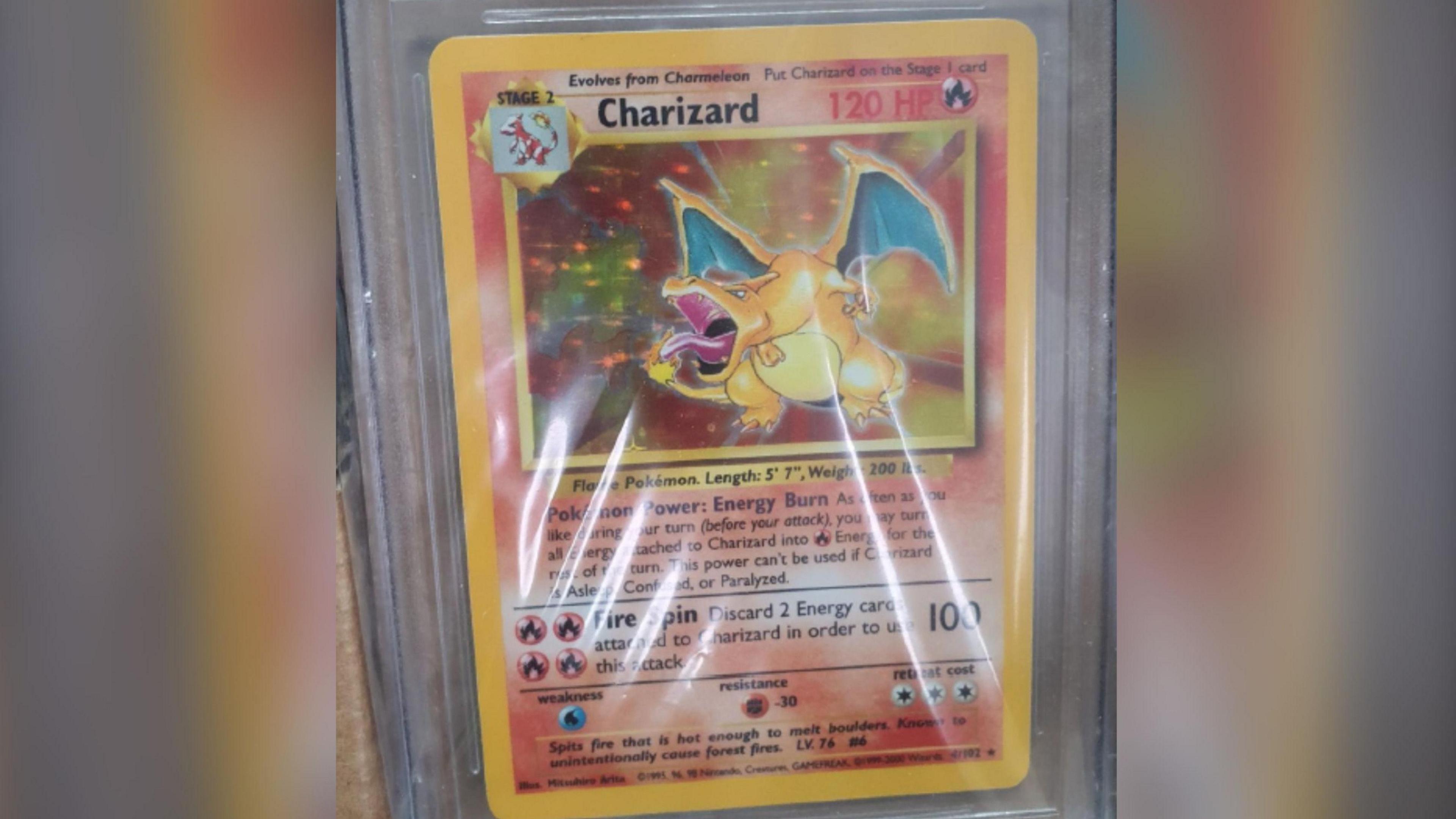 A close up of a Charizard Pokemon card showing a big image of a golden dragon breathing fire