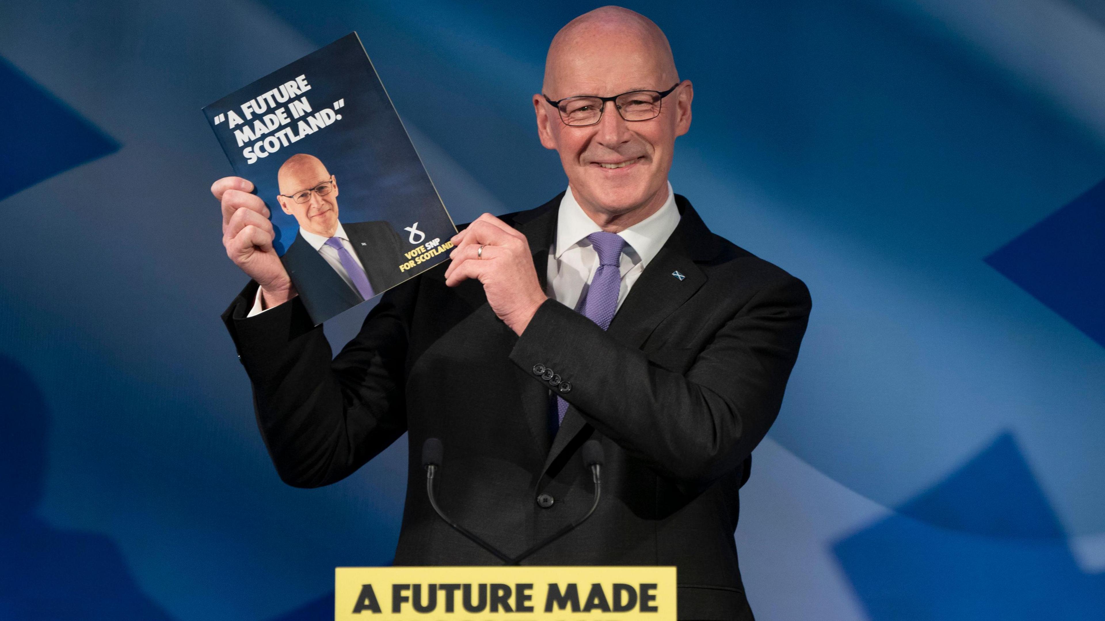 John Swinney holds the SNP manifesto at the launch event