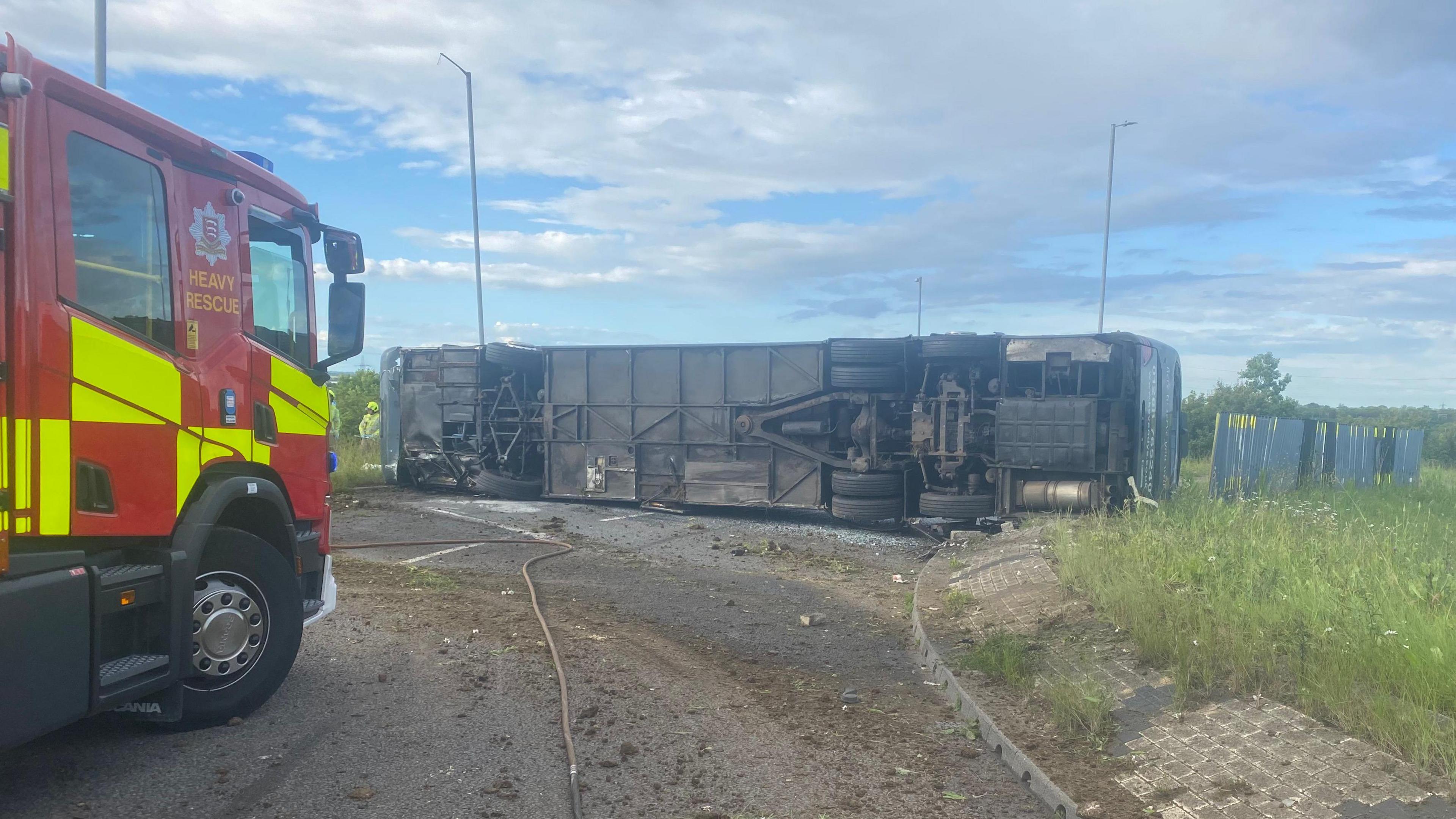 A fire engine next to the overturned coach