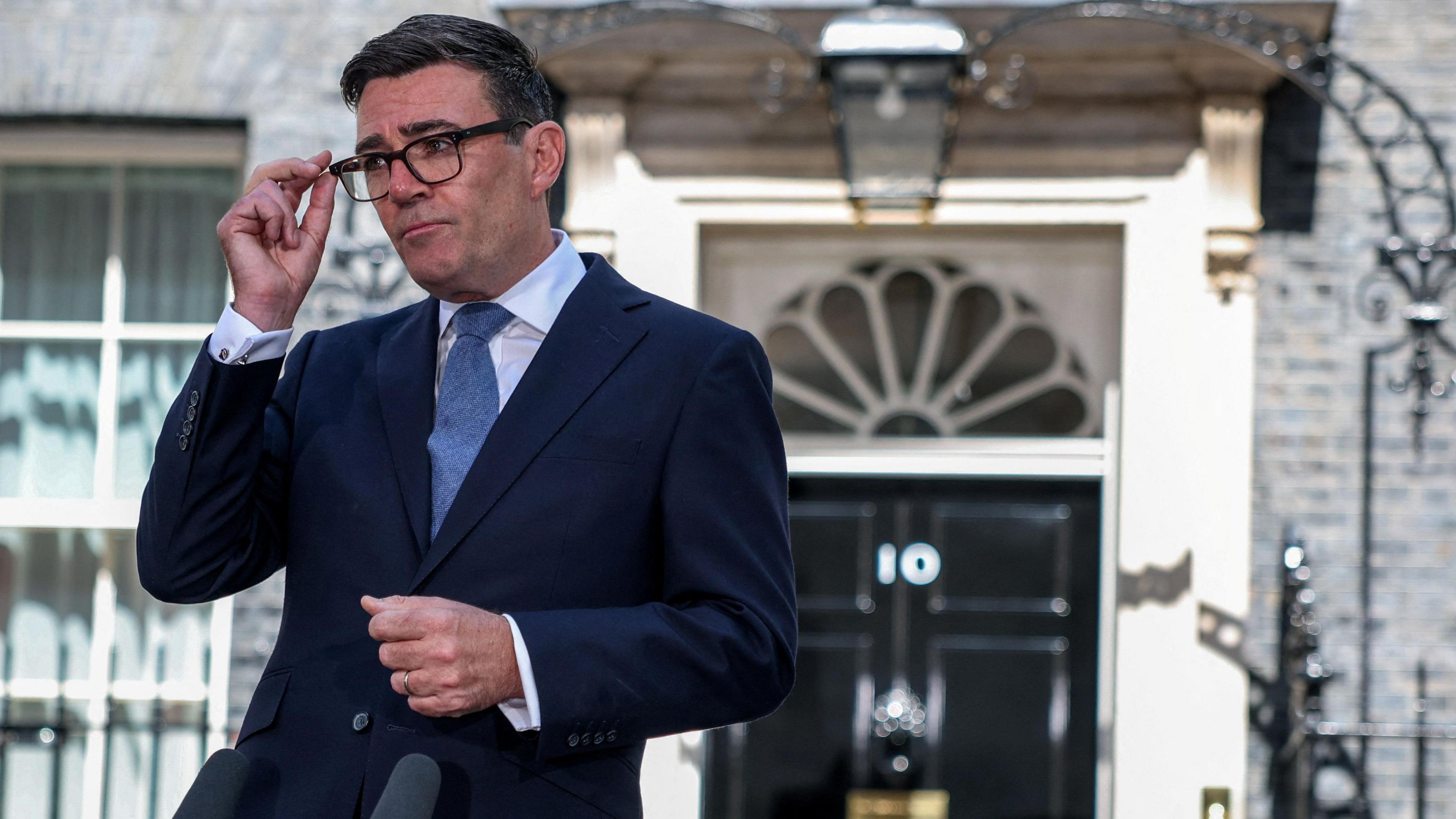 Britain's newly appointed Prime Minister Andy Burnham adjusts his glasses as he delivers a speech outside 10 Downing Street