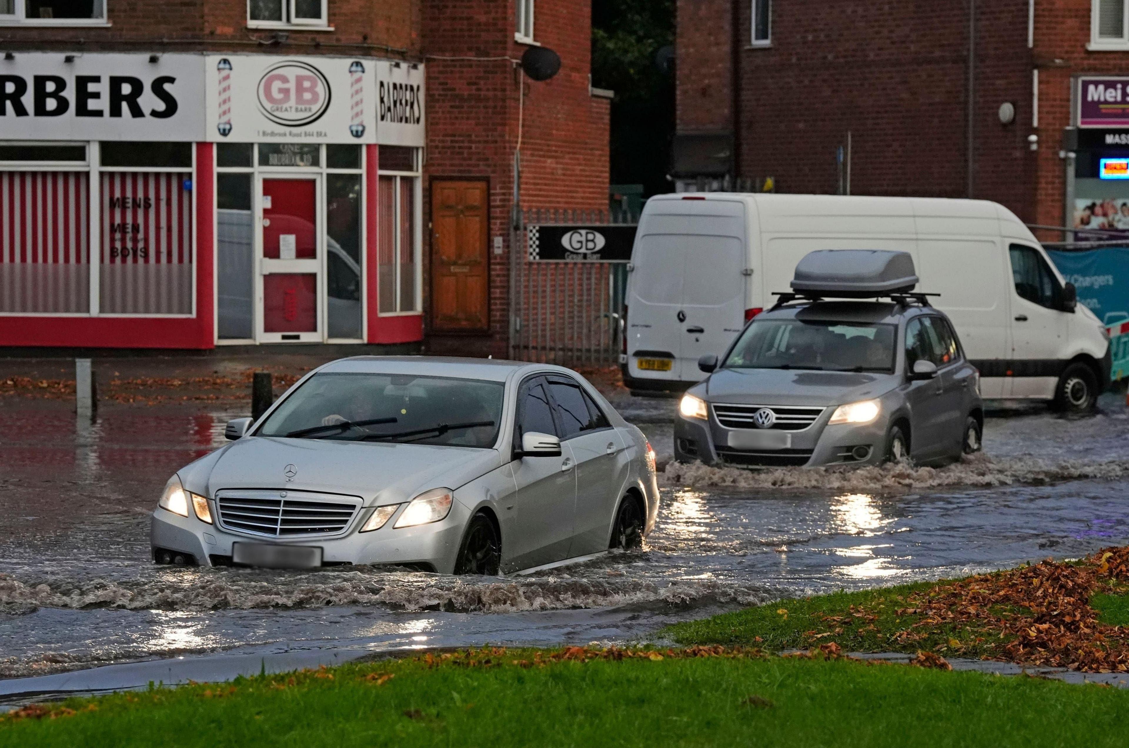 Two cars driving through water on a flooded road in Birmingham