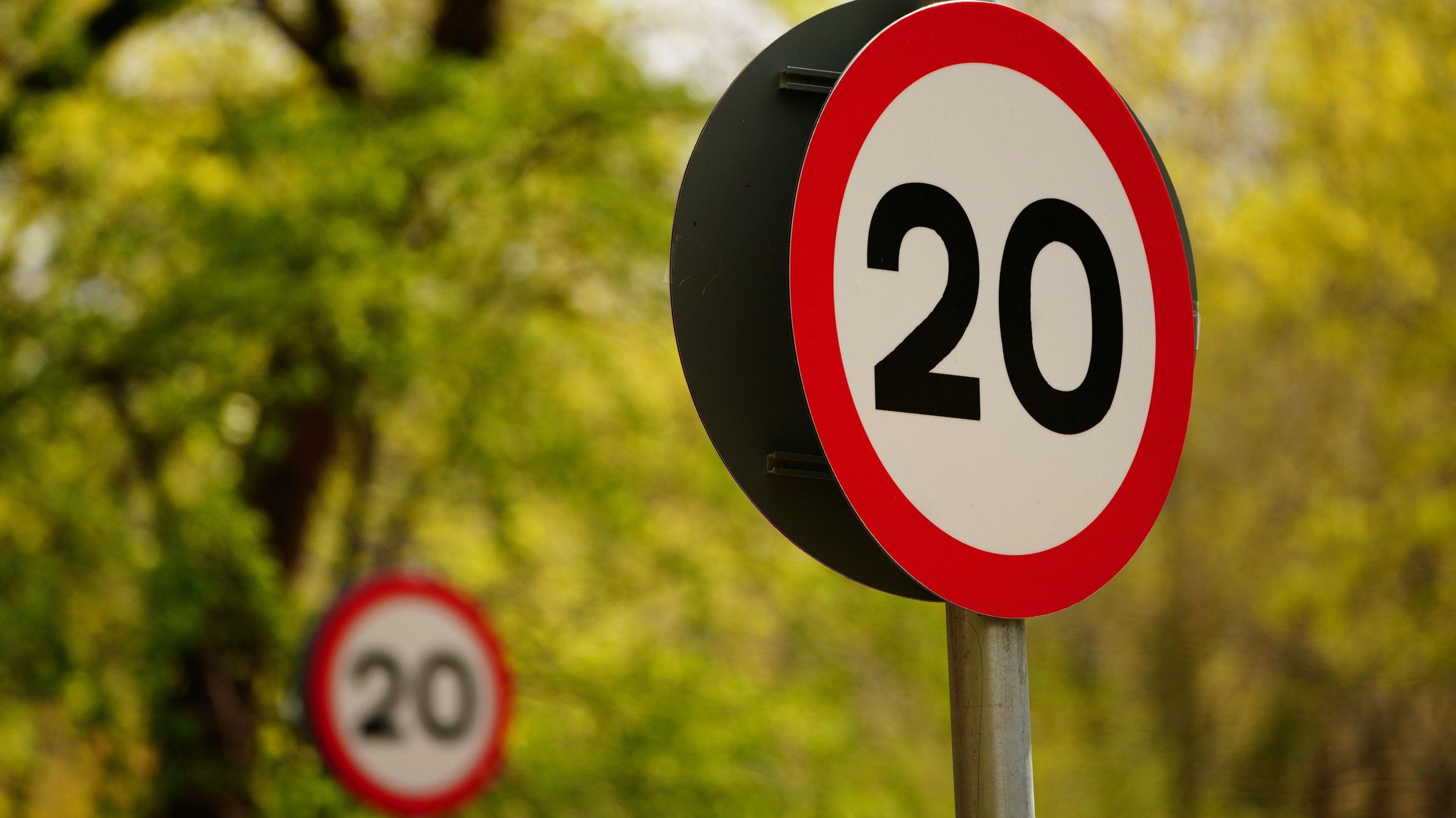 20mph signs with leafy green trees in the background