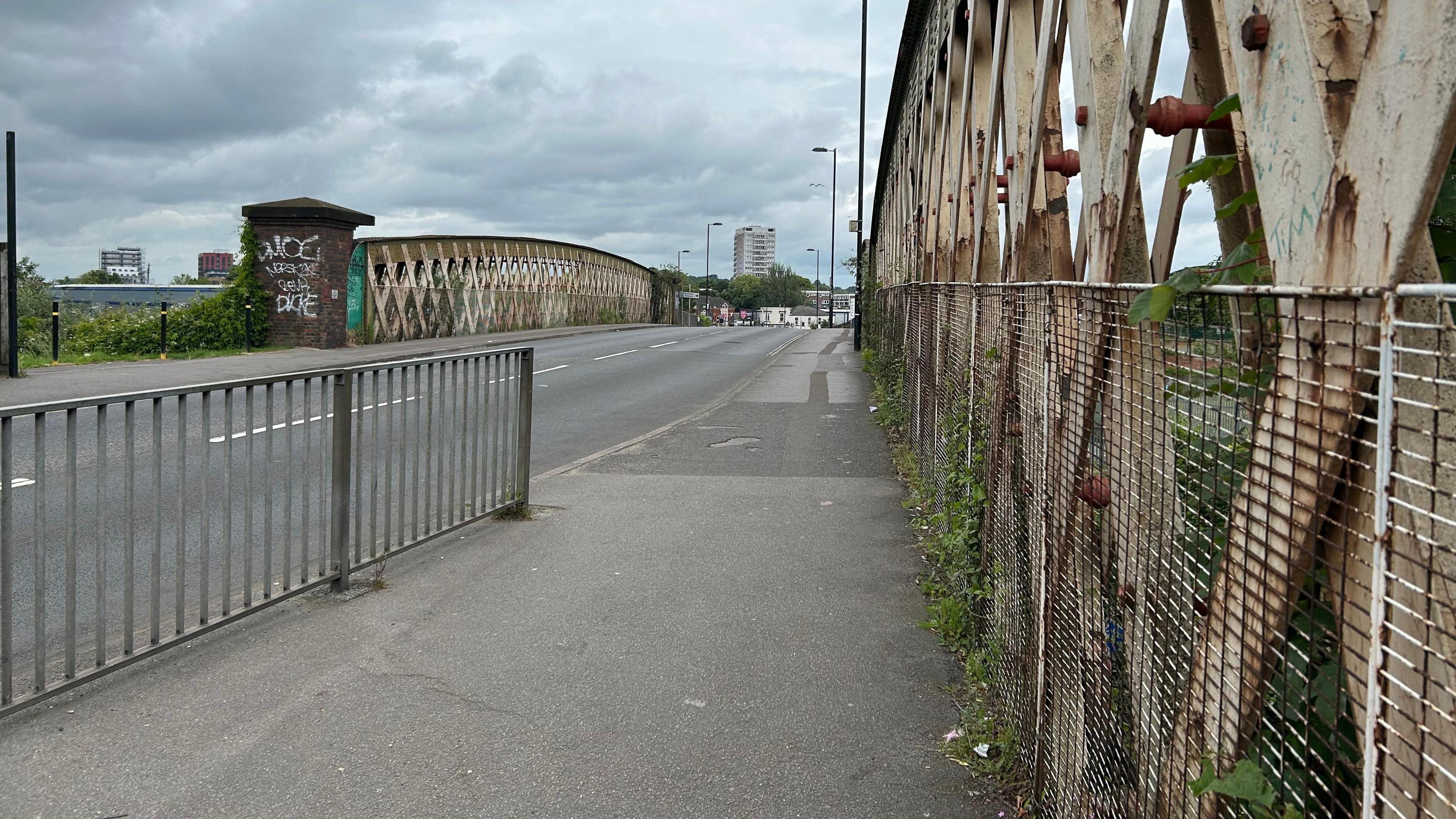A view taken from the pavement of the road and walkways over the aging rail bridge. 