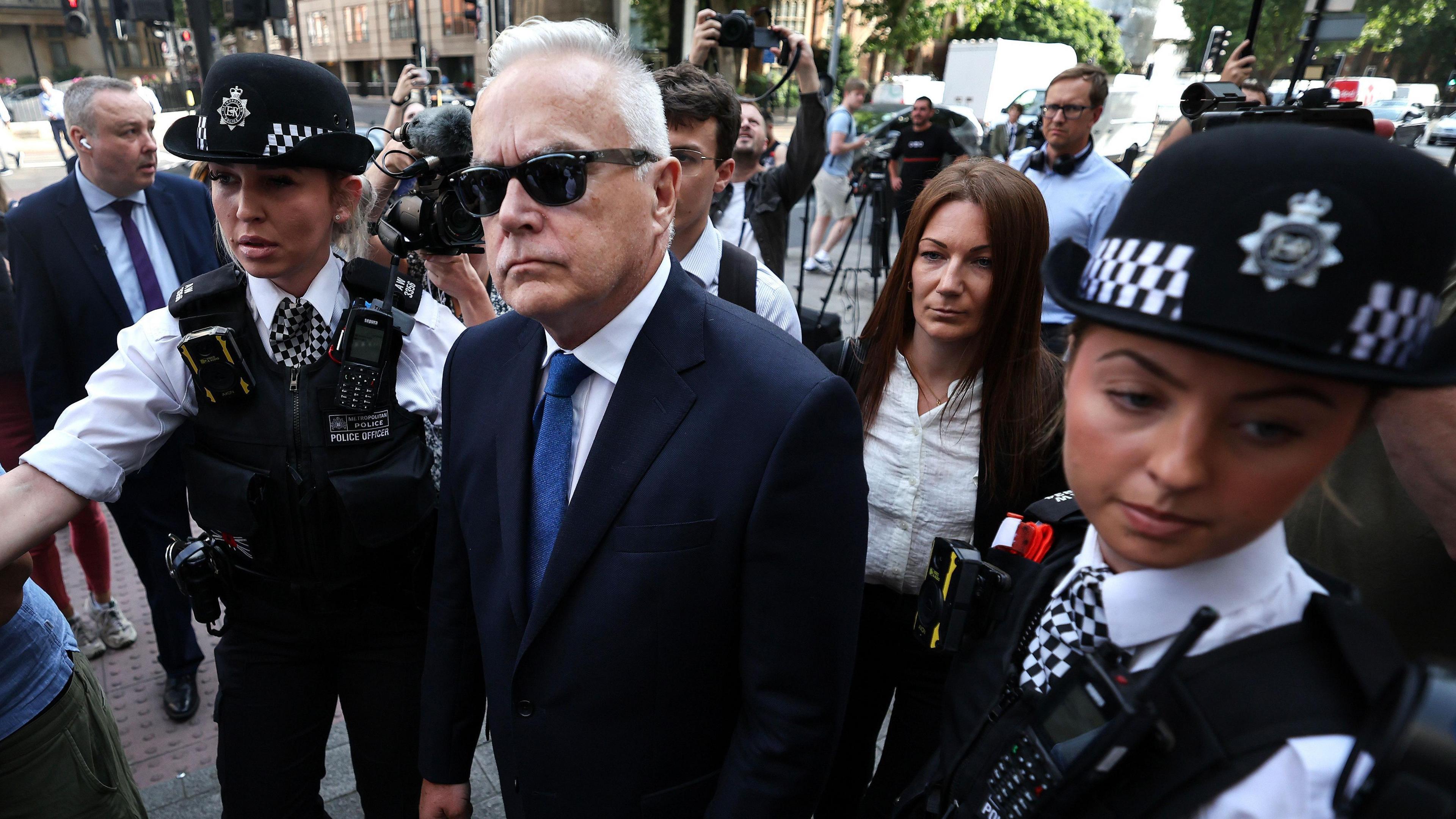 Huw Edwards is seen alongside police officers
