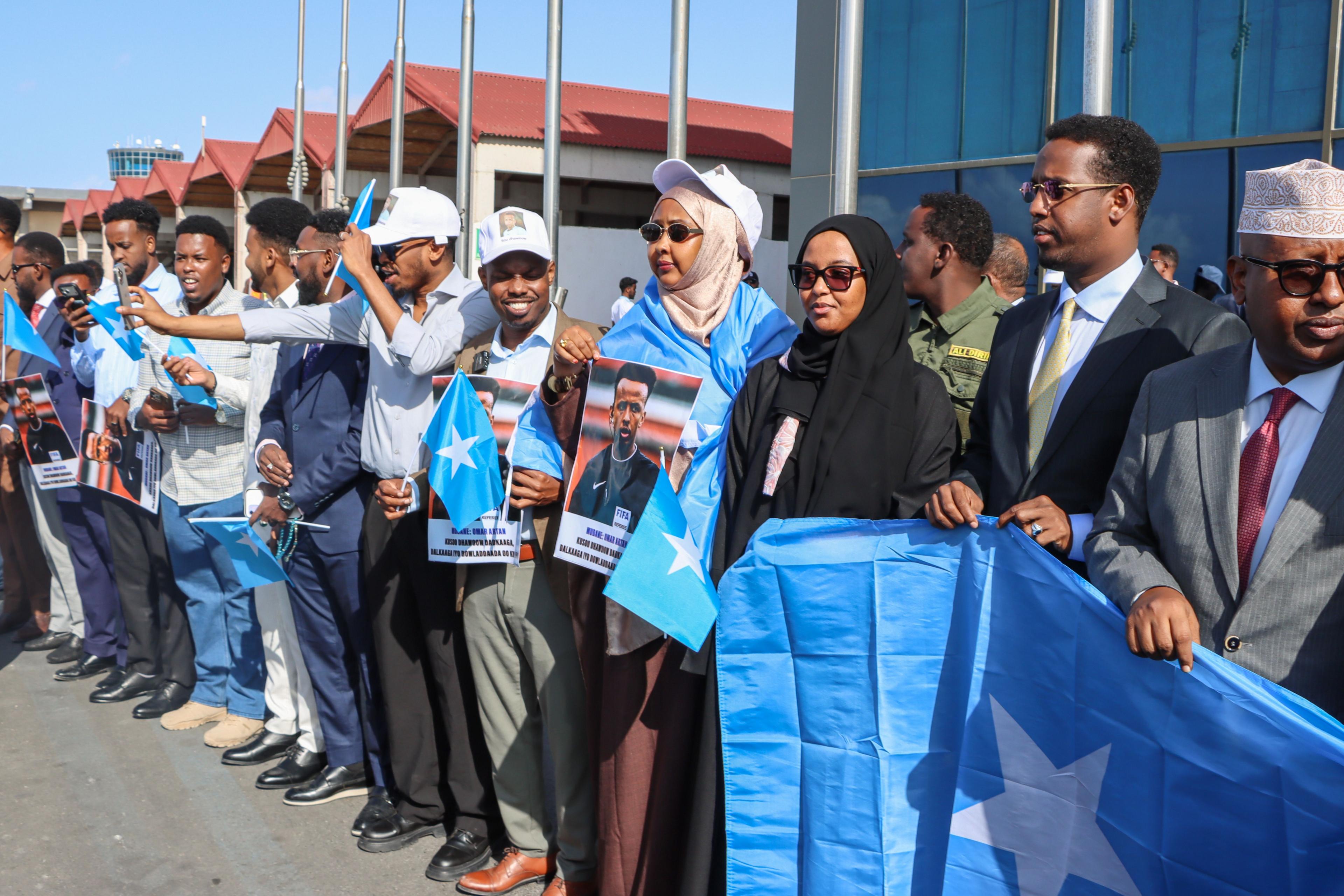 A assemblage of radical holding Somalia flags (pale bluish with a achromatic star) and pictures of Omar Artan