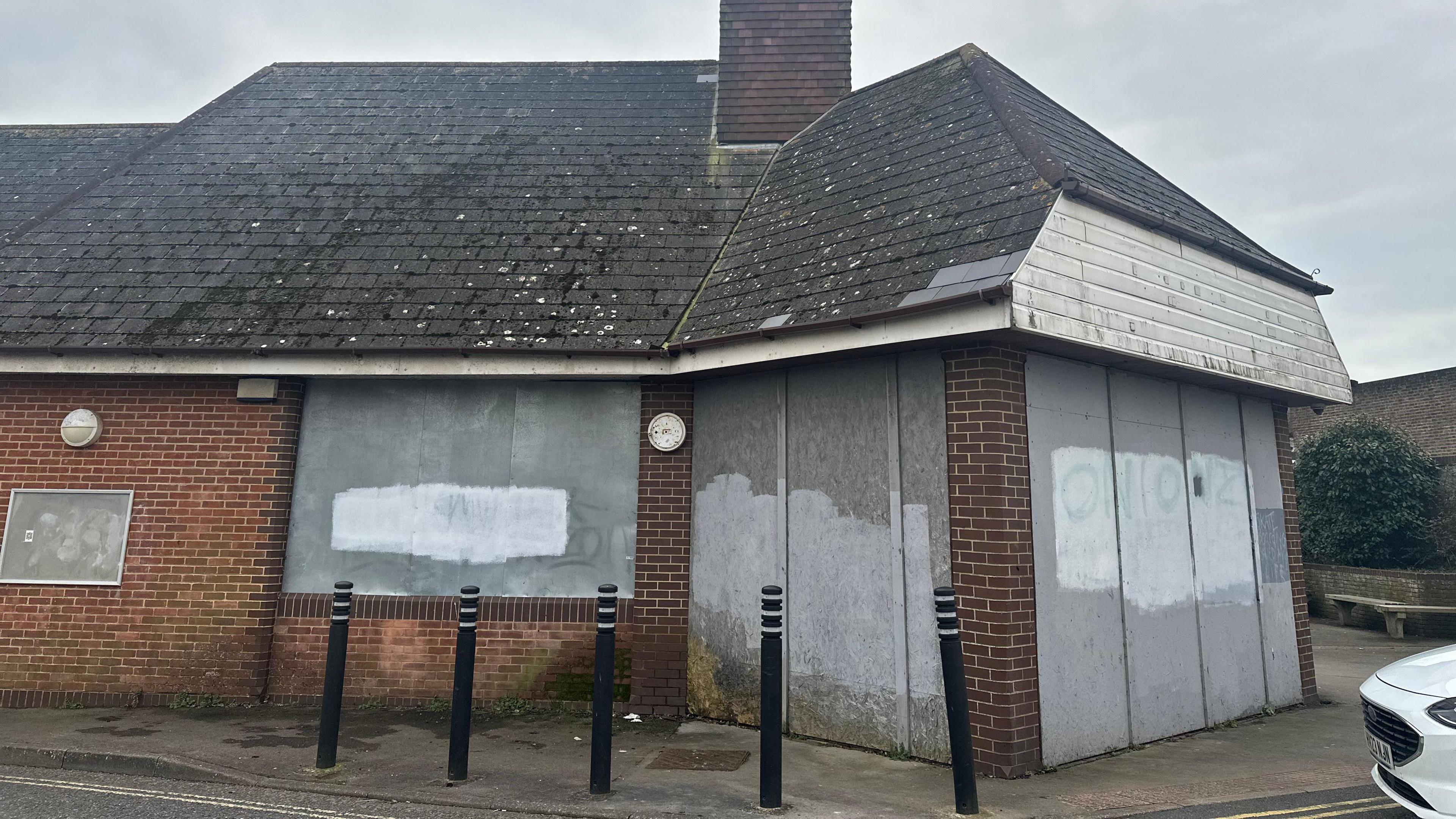 A dilapidated brick building which has been boarded up.