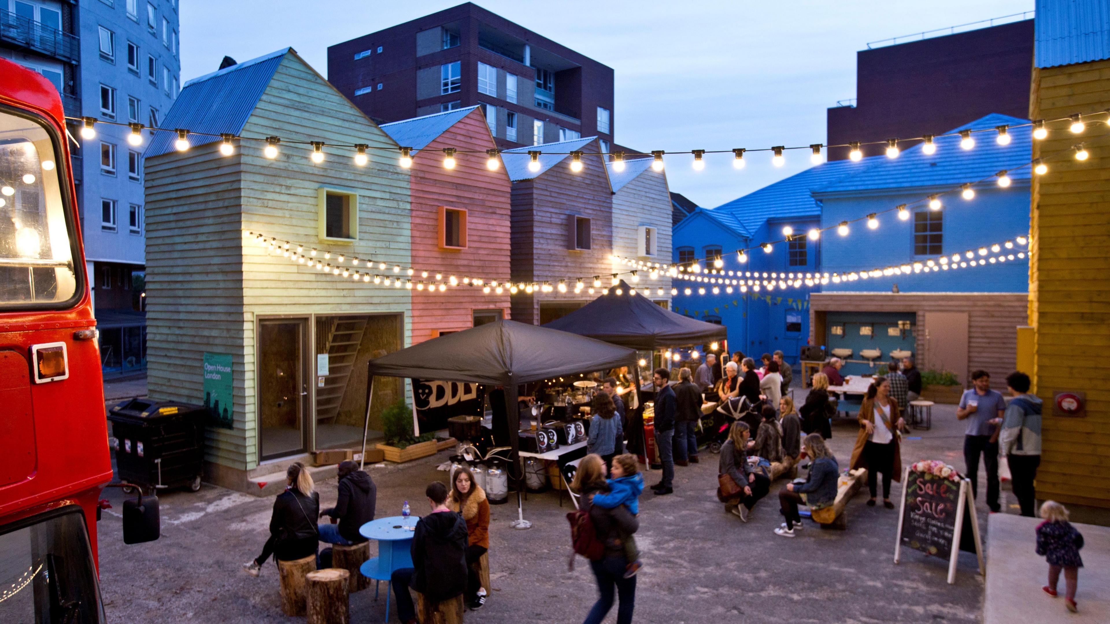 A square in Haringey, London, with shoppers, people eating, drink and standing between several new buildings