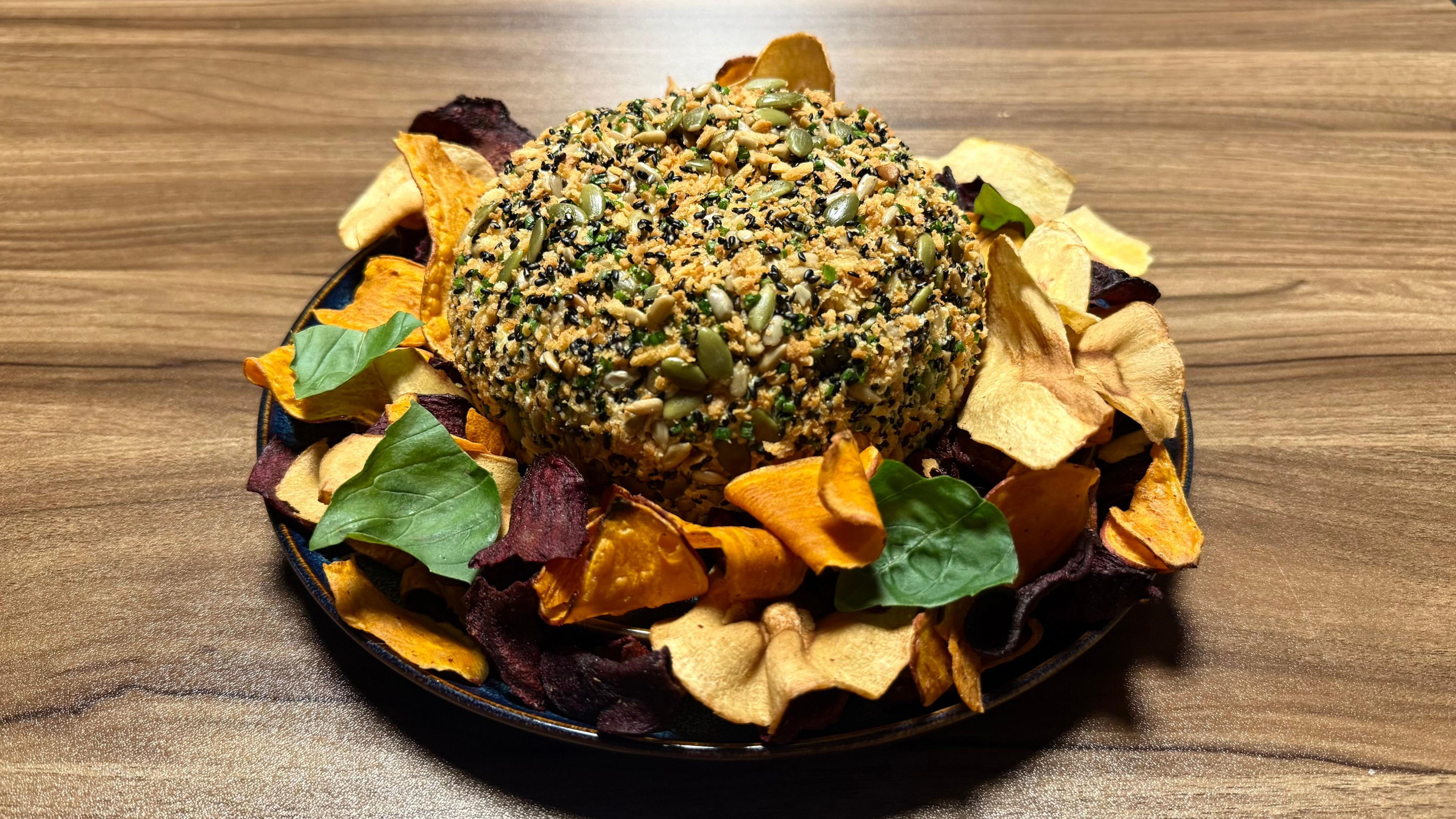 Image of a cheese ball. Cheese ball is surrounded by vegetable crisps.