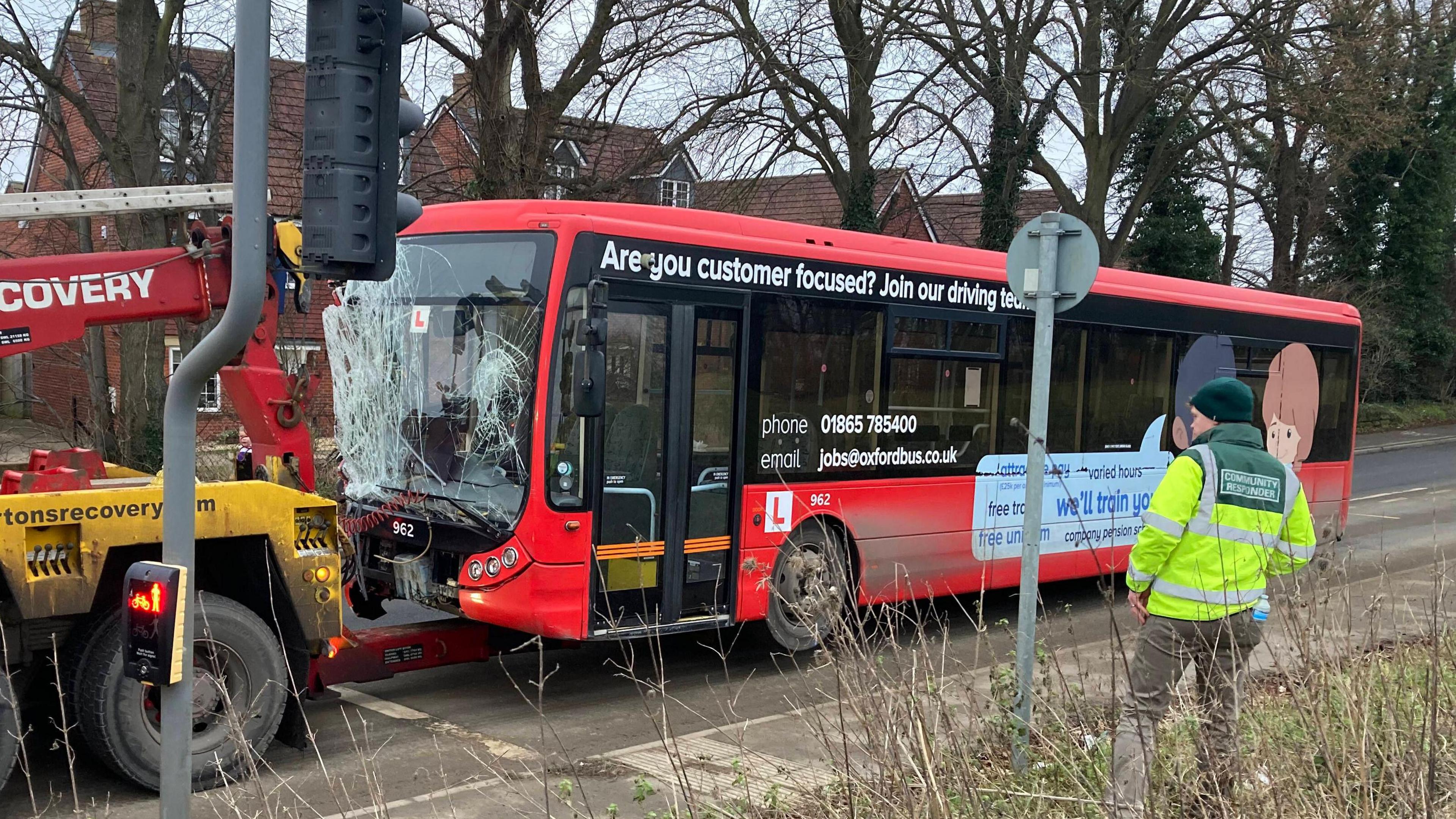 A smashed up bus being towed away on the back of a yellow tow truck