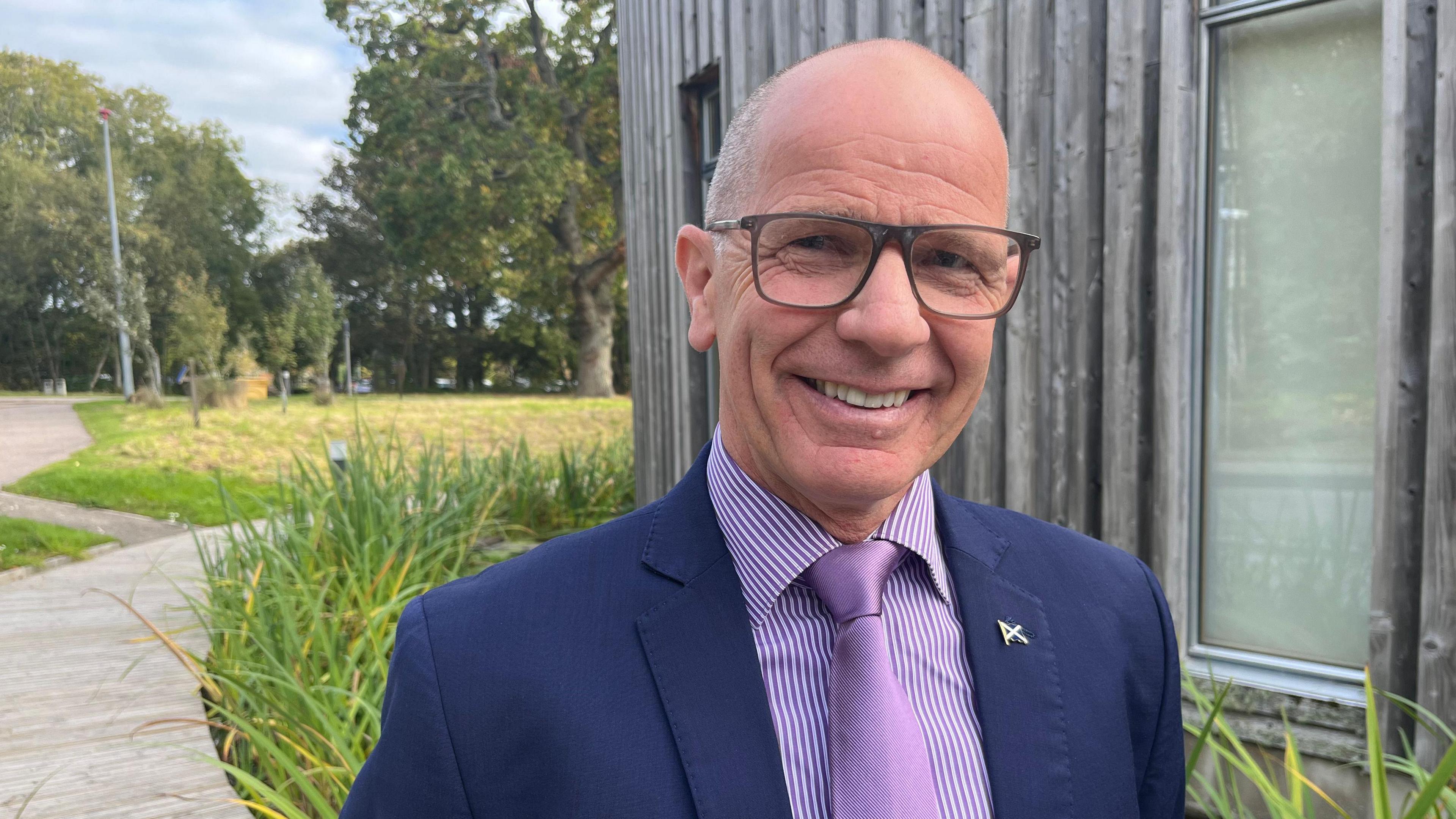 Minister for Agriculture and Connectivity, Jim Fairlie, smiling and wearing a blue suit and purple tie