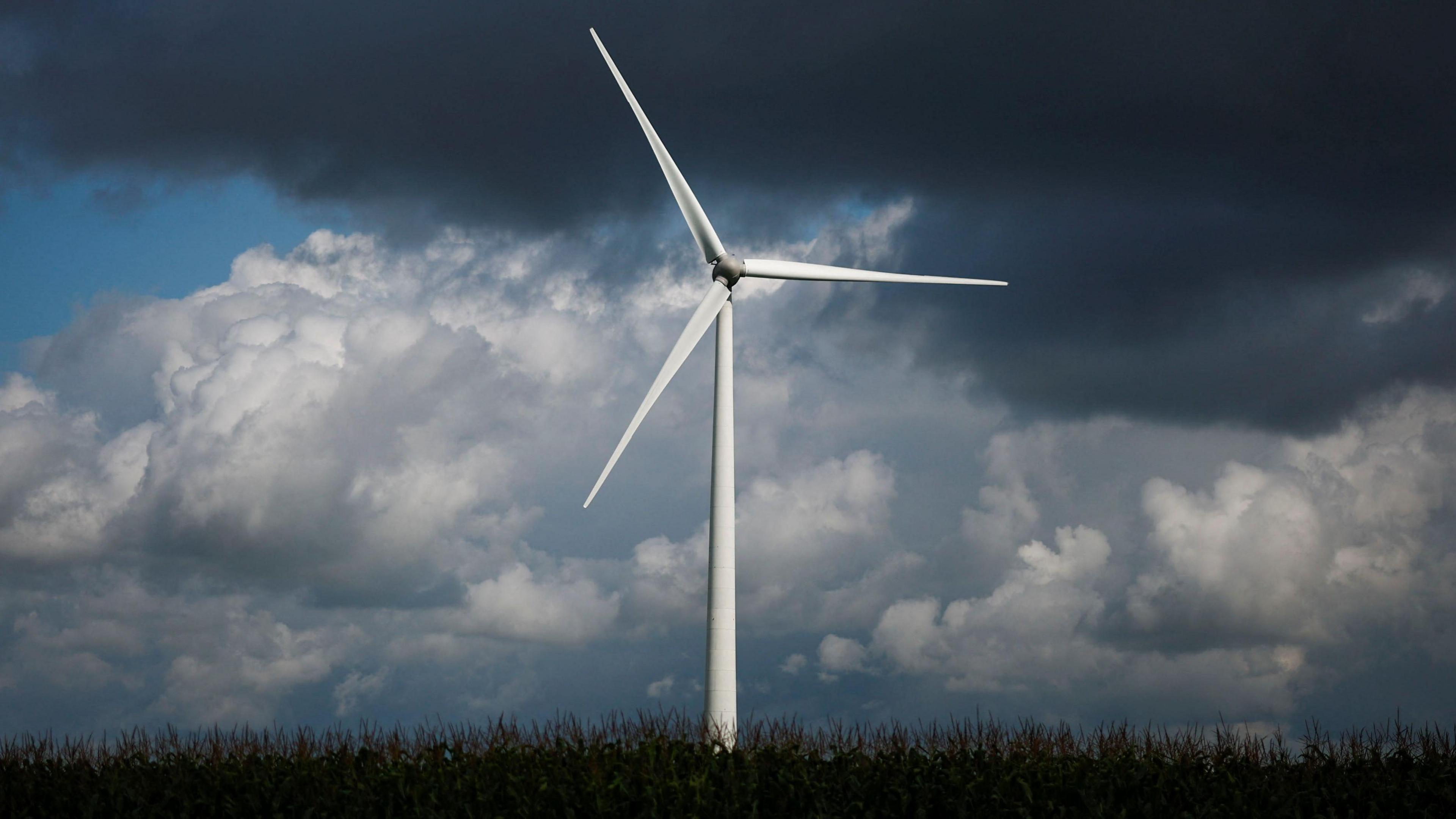 A wind turbine against a backdrop of dark clouds.