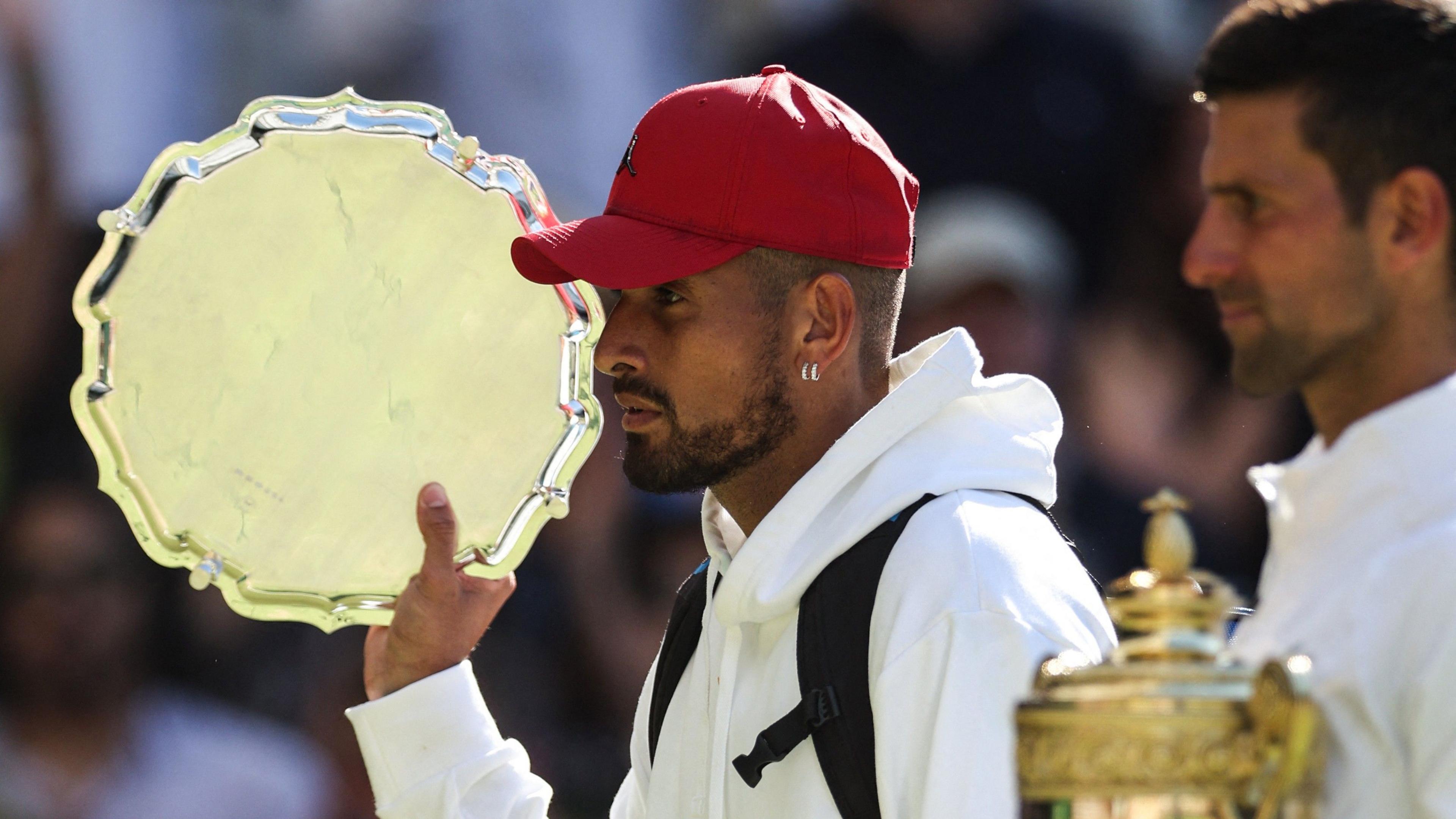 Nick Kyrgios walks off with the Wimbledon singles runner-up trophy after losing the 2022 final to Novak Djokovic