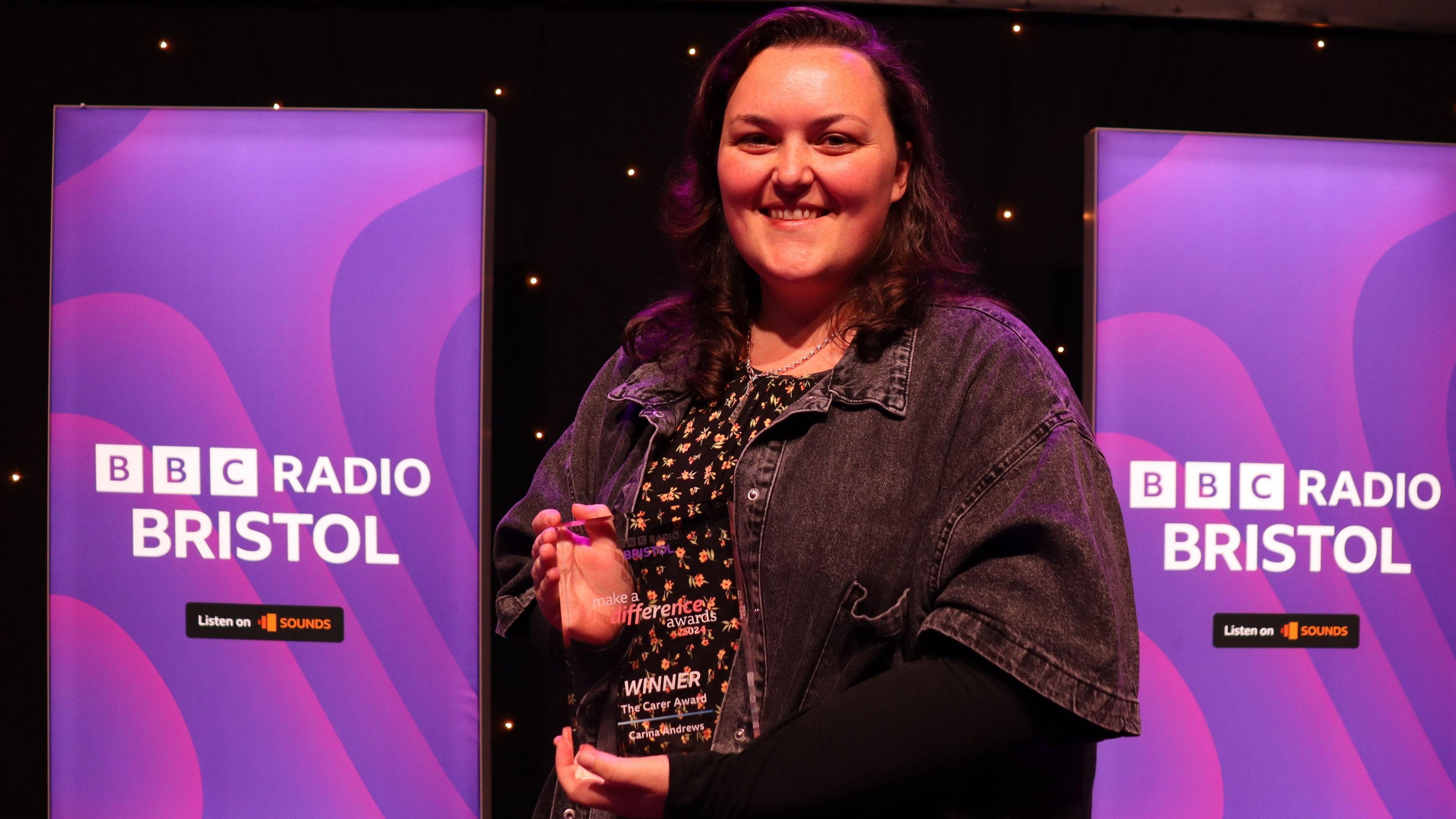 Carina Andrews holding her award on a stage.