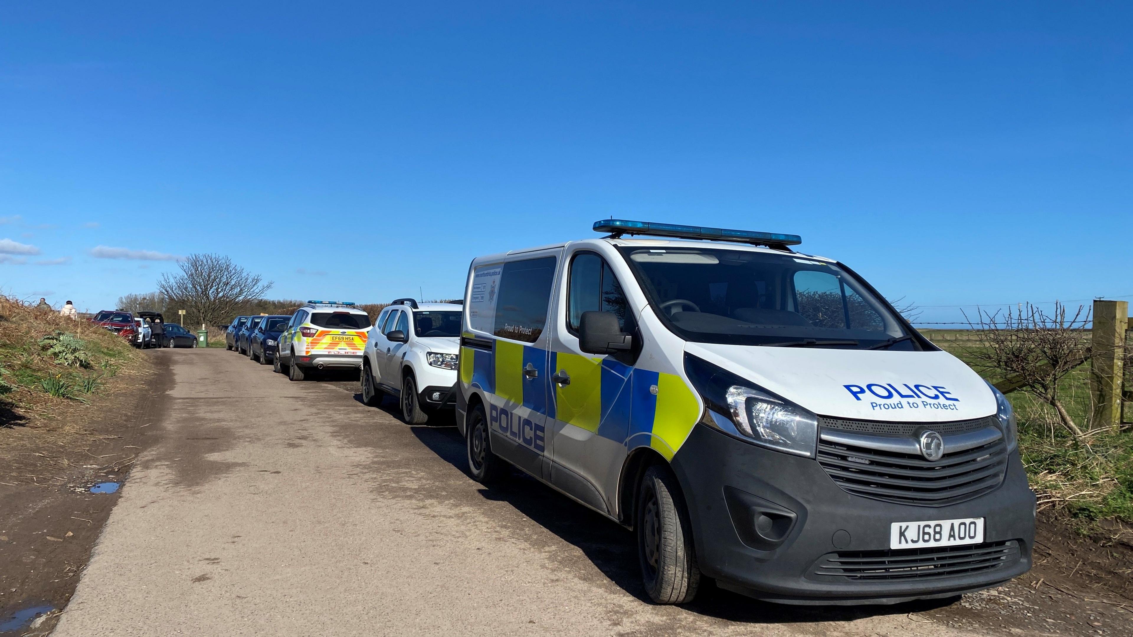 Two police vehicles parked up along a coastal road