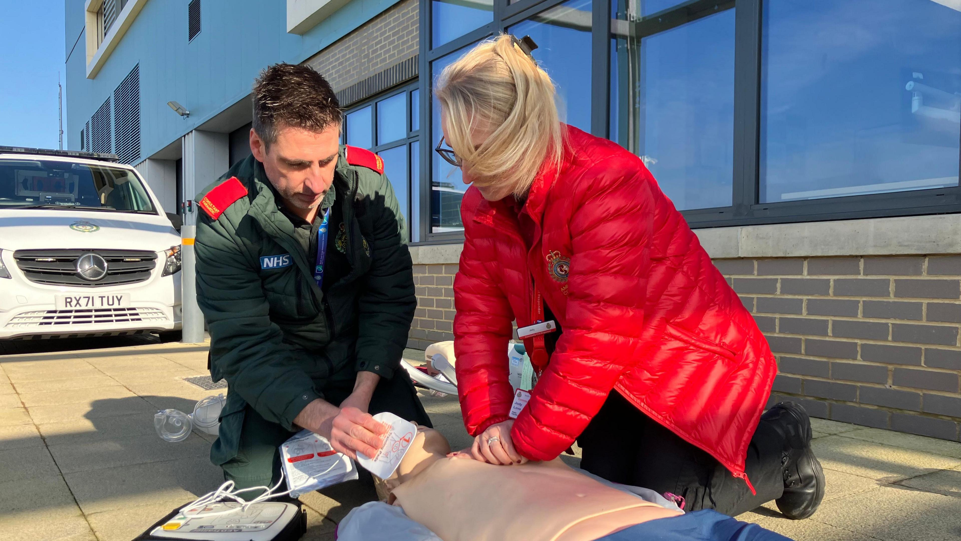 To people on the ground demonstrating how to perform CPR on a CPR dummy