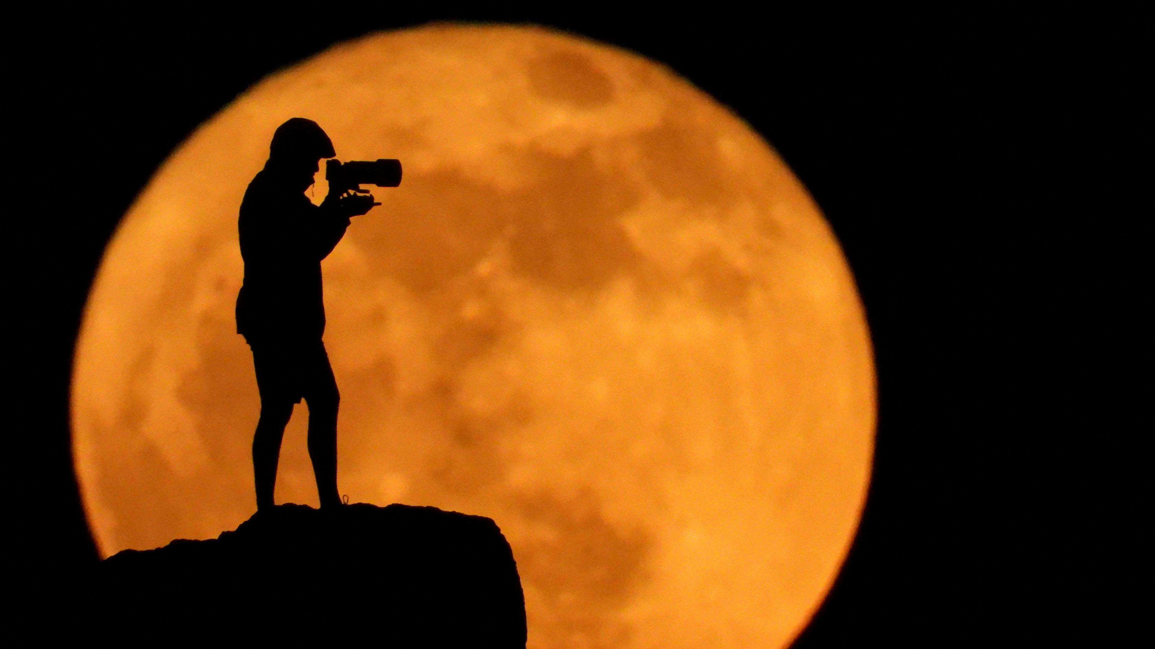 A photographer silhouetted against the Strawberry Moon in Gran Canaria.