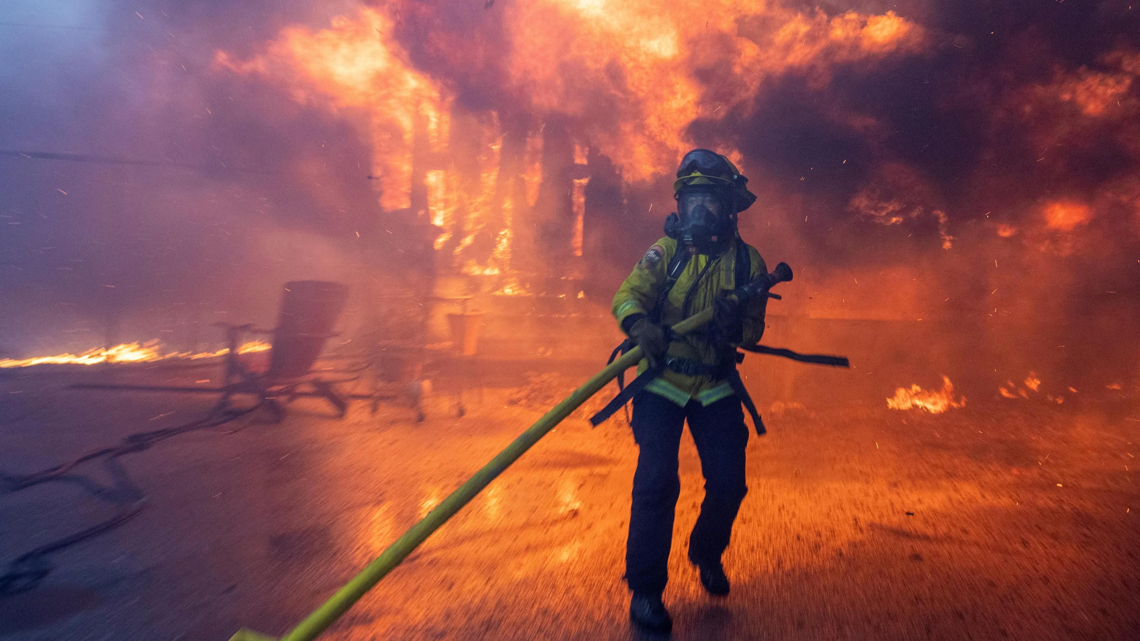 A firefighter battles the Palisades Fire as it burns during a windstorm on the west side of Los Angeles.