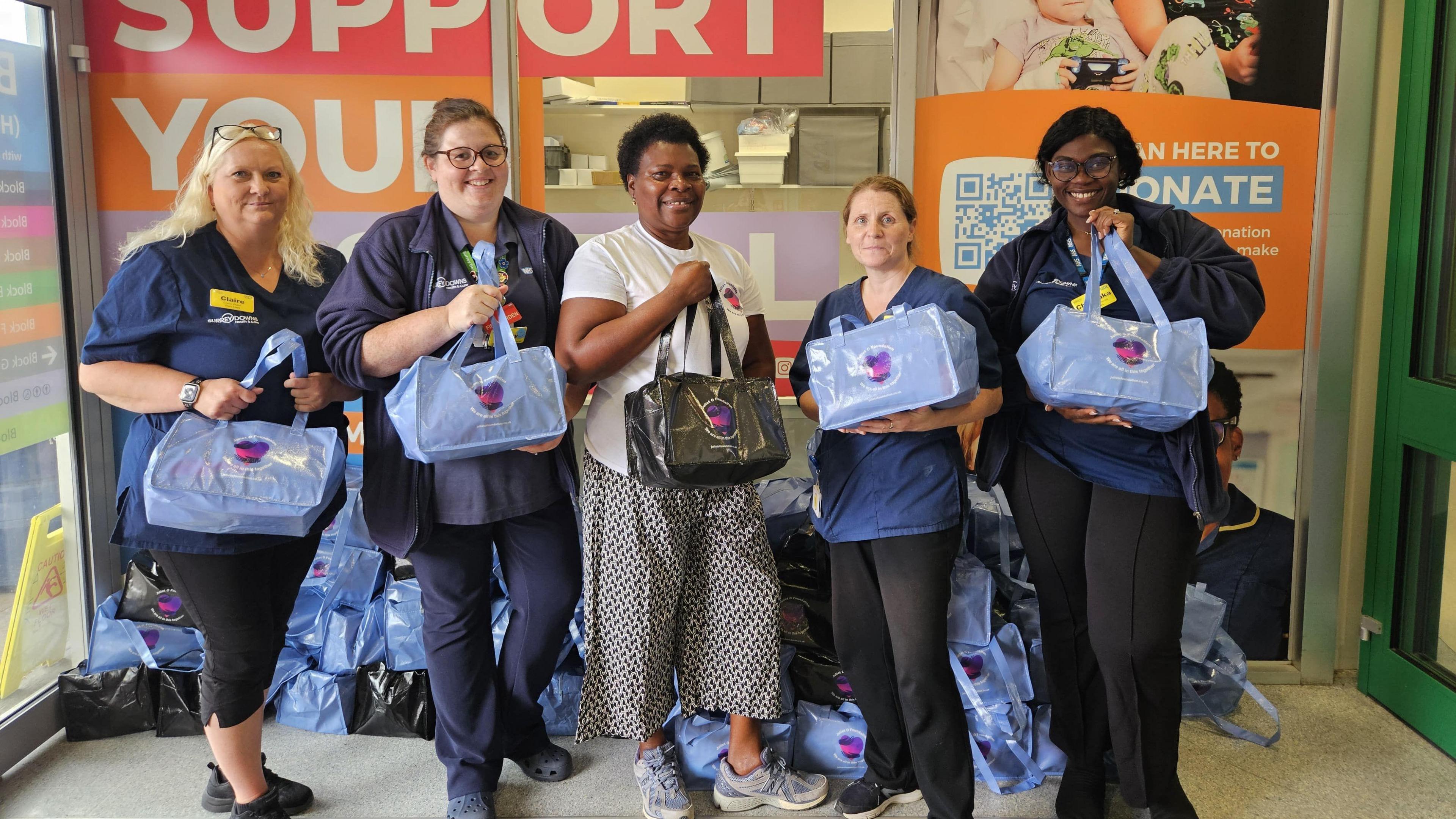 Juliet and four members of staff from the Epsom Hospital hold bags provided by the charity